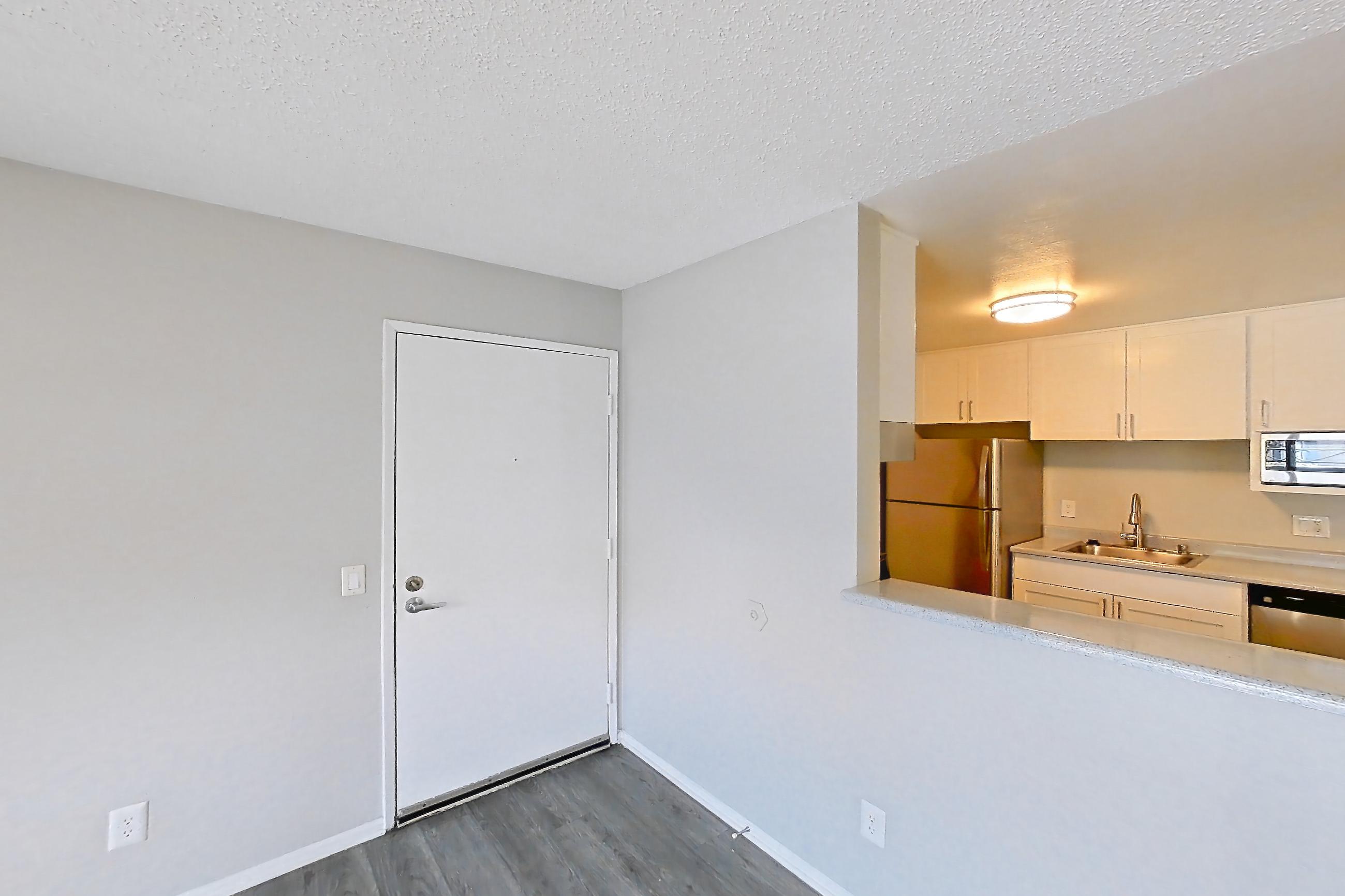 Living room with dark wood-finish flooring, dishwasher, refrigerator, and stainless steel appliances, Apartment 16-03 at Avana Rancho Cucamonga