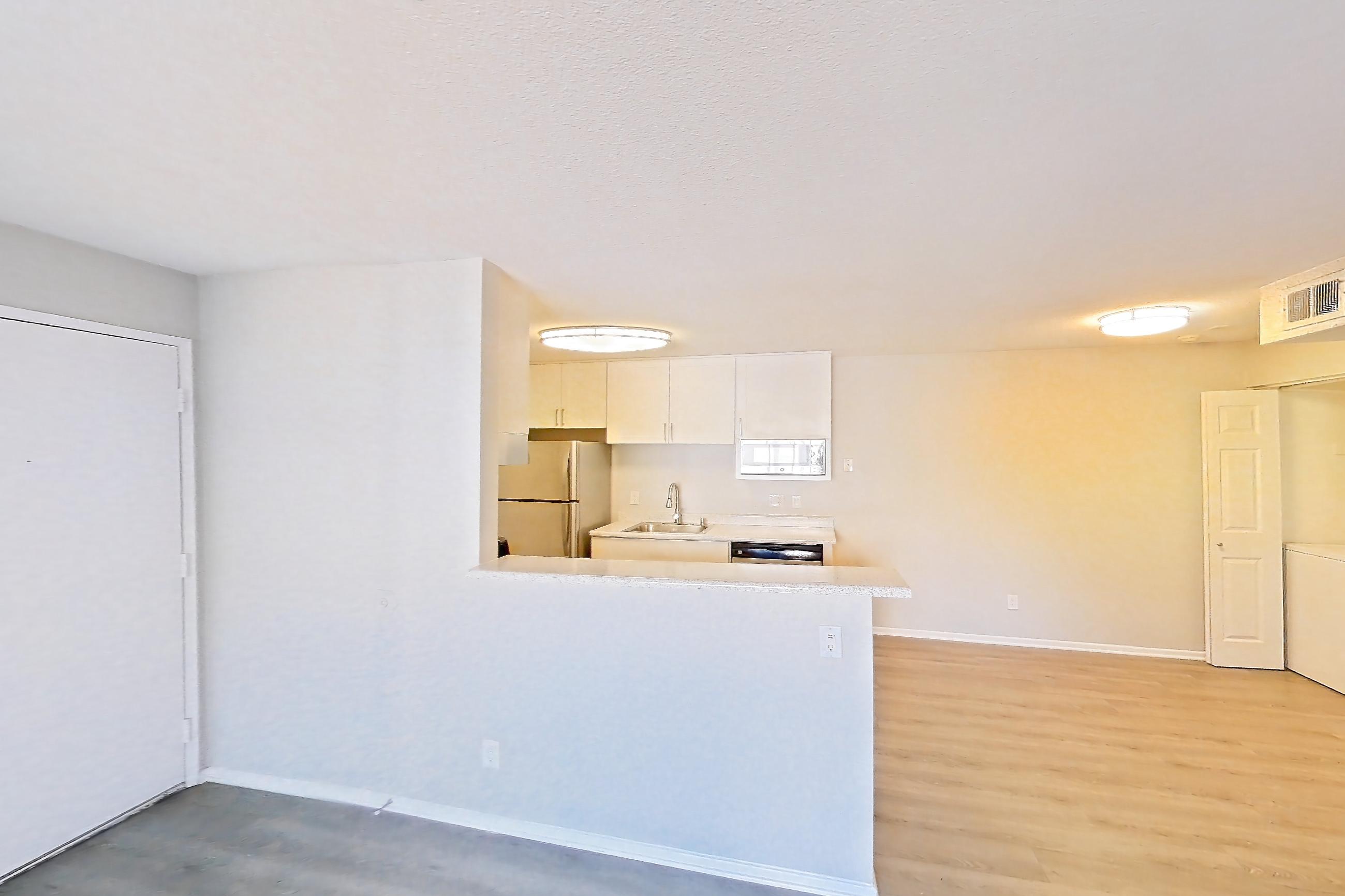 Living room with dark wood-finish flooring, refrigerator, and white appliances, Apartment 16-06 at Avana Rancho Cucamonga