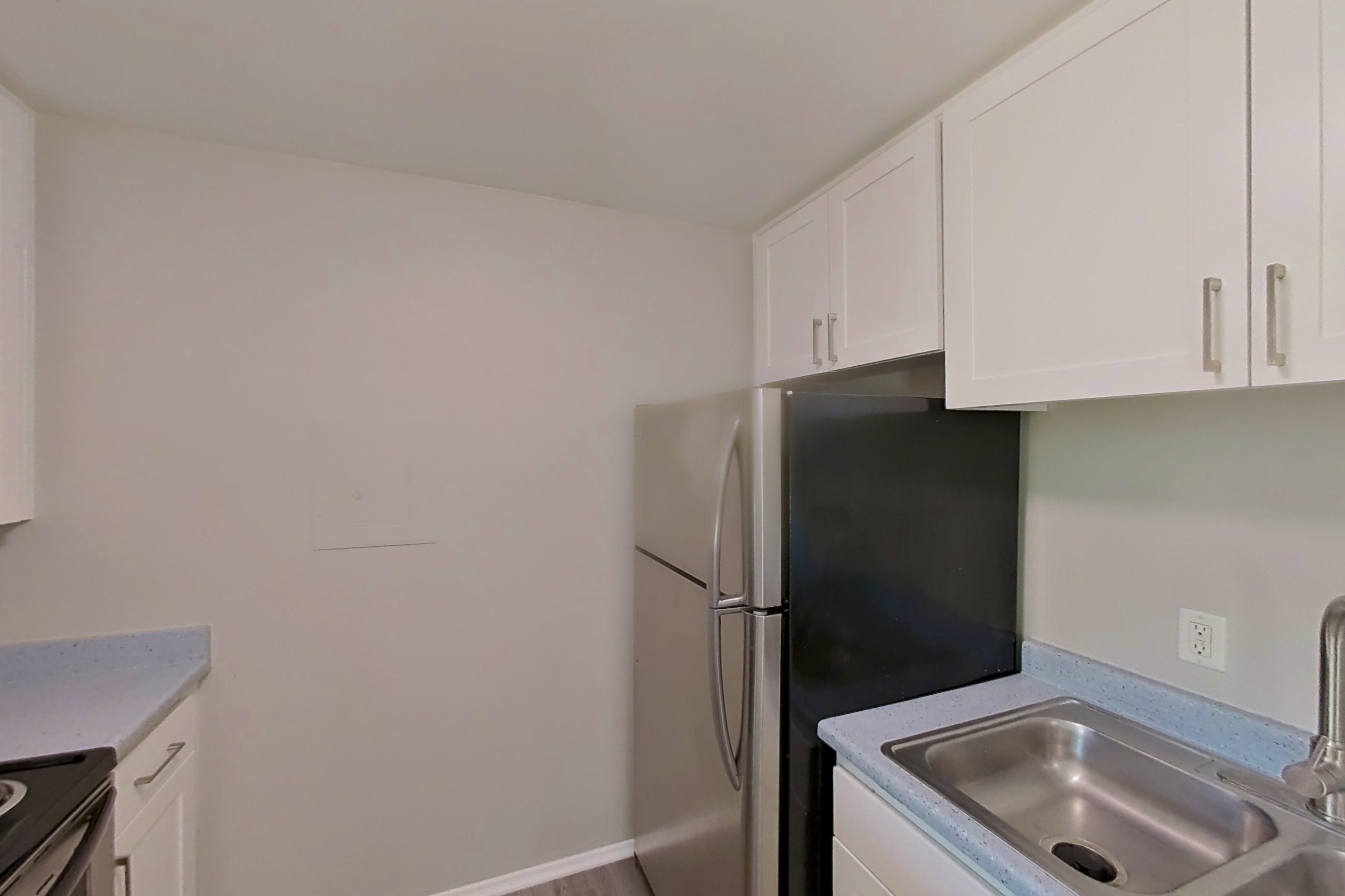 Kitchen with dishwasher, electric range, light countertops, light stone countertops, light wood-finish flooring, microwave, oven/range, refrigerator, and stainless steel appliances, Apartment 16-23 at Avana Rancho Cucamonga