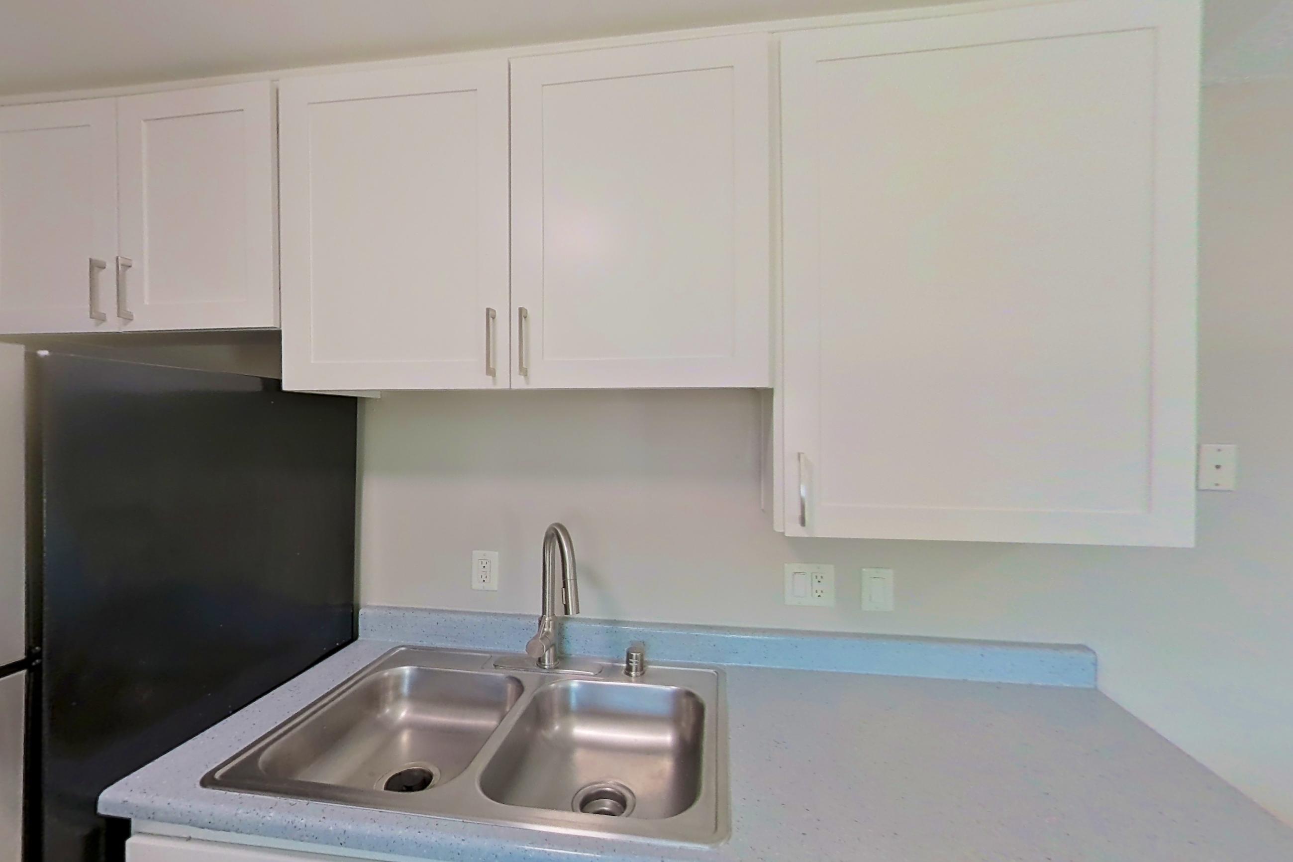 Kitchen with dishwasher, electric range, light countertops, light stone countertops, light wood-finish flooring, microwave, oven/range, refrigerator, and stainless steel appliances, Apartment 16-23 at Avana Rancho Cucamonga