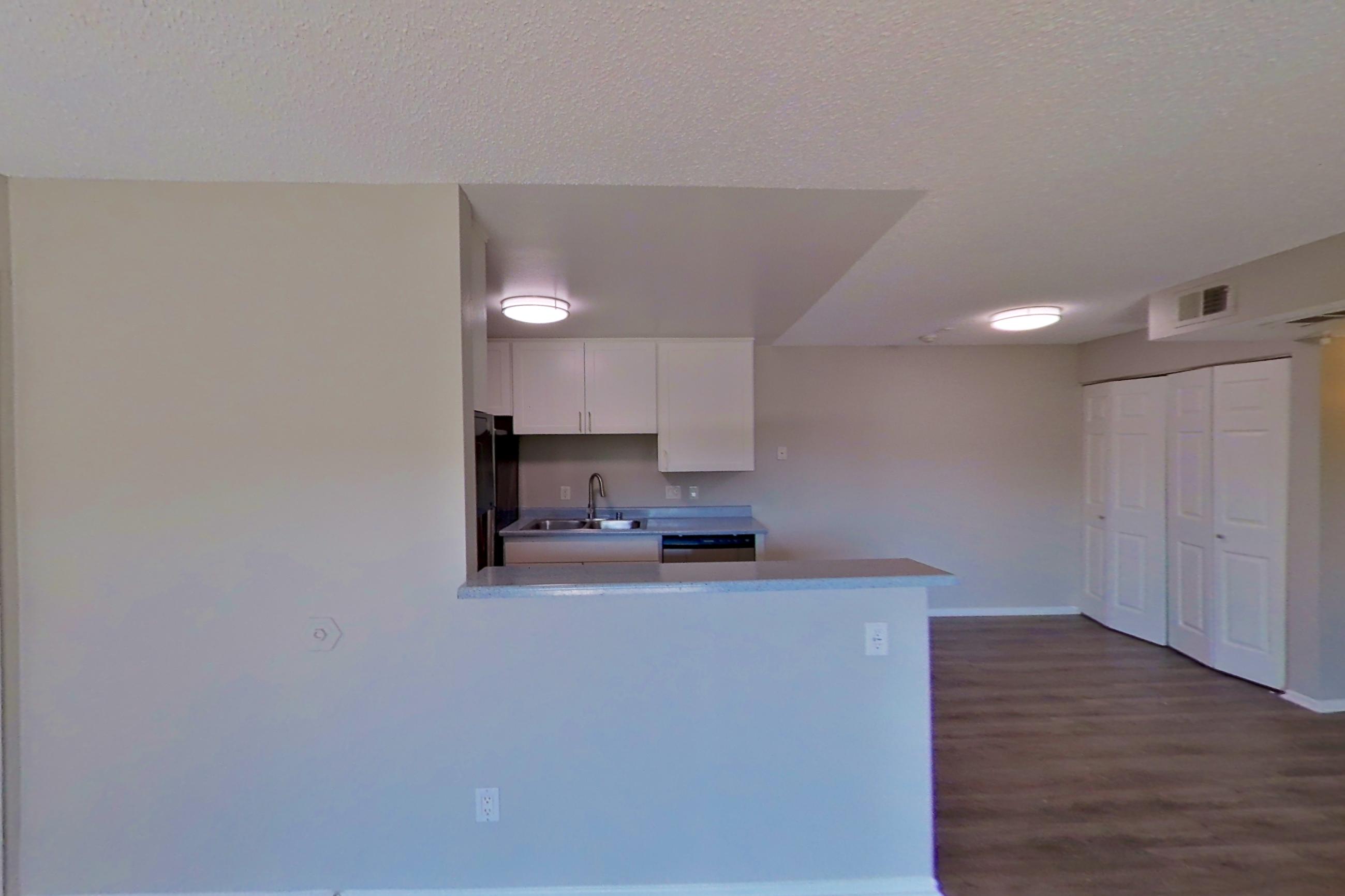 Living space with dark wood-finish flooring, dishwasher, light countertops, and stainless steel appliances, Apartment 16-23 at Avana Rancho Cucamonga