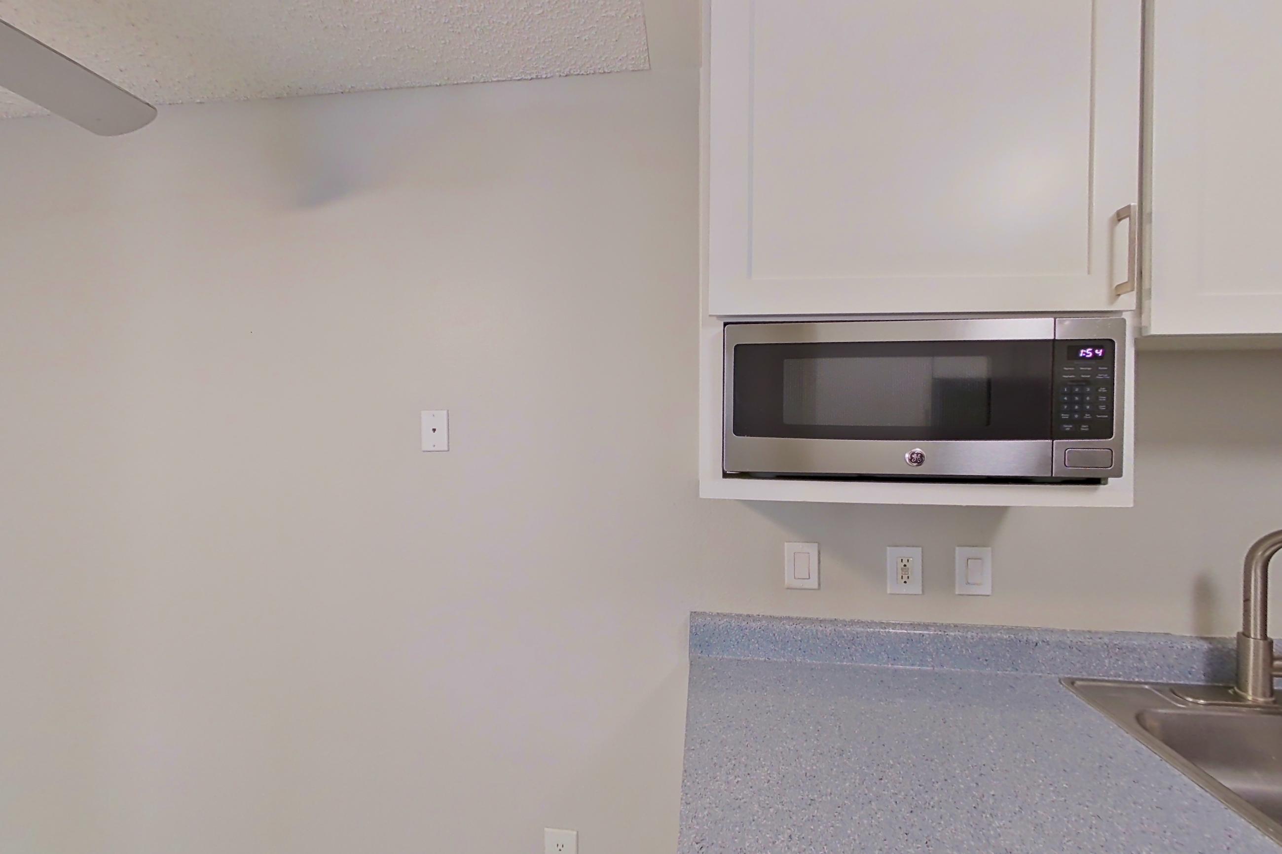 Kitchen with dishwasher, electric range, light stone countertops, light wood-finish flooring, microwave, oven/range, stainless steel appliances, and white appliances, Apartment 18-06 at Avana Rancho Cucamonga
