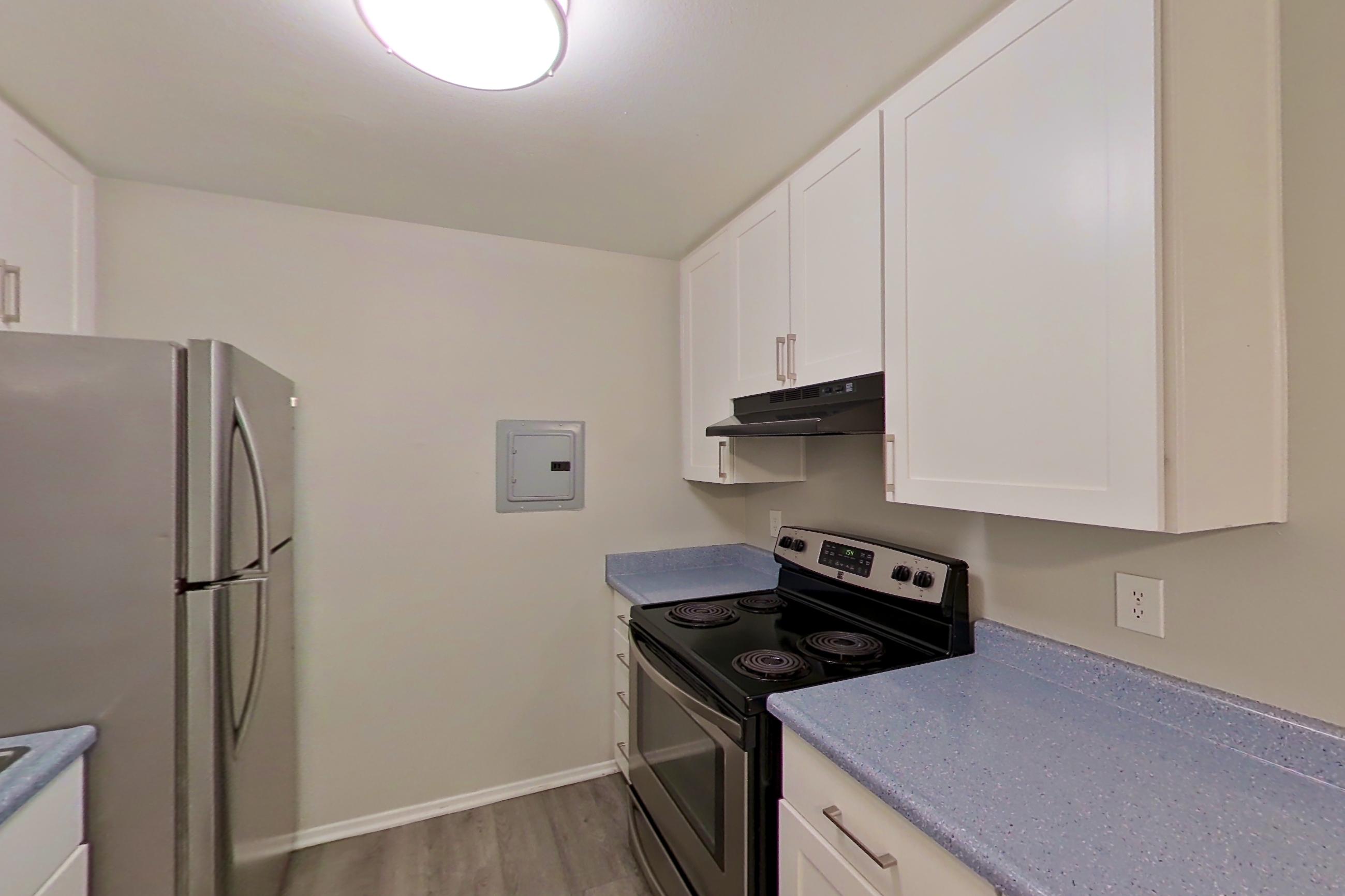 Kitchen with dishwasher, electric range, light stone countertops, light wood-finish flooring, microwave, oven/range, stainless steel appliances, and white appliances, Apartment 18-06 at Avana Rancho Cucamonga