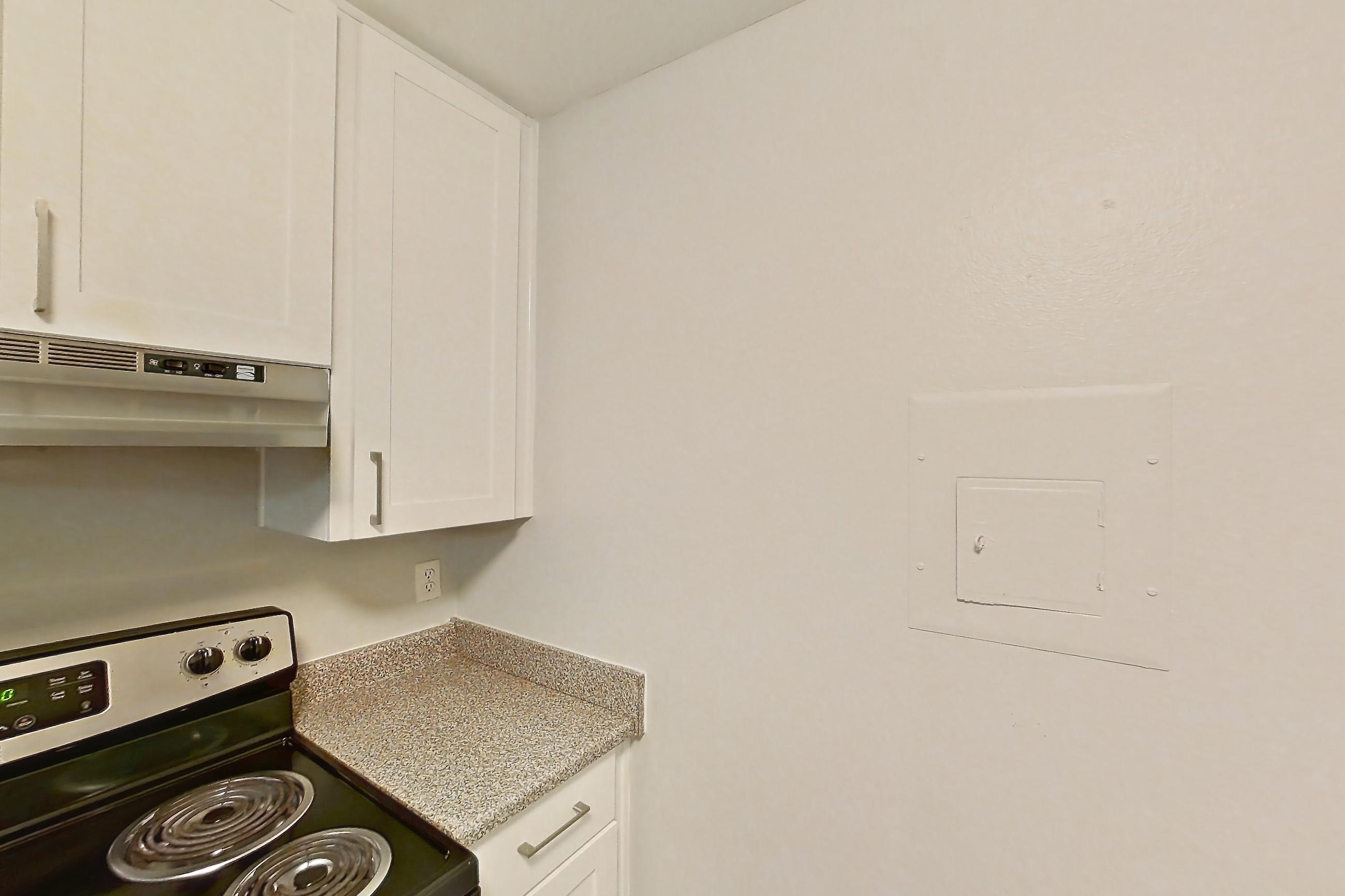 Kitchen with electric range, light countertops, light stone countertops, light wood-finish flooring, oven/range, refrigerator, and stainless steel appliances, Apartment 19-02 at Avana Rancho Cucamonga