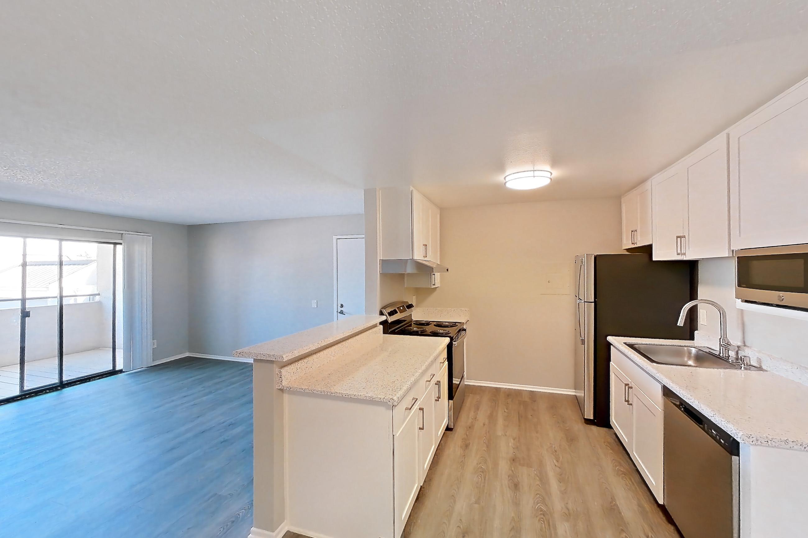 Dining room with dark wood-finish flooring, dishwasher, in-unit laundry, light stone countertops, light wood-finish flooring, and stainless steel appliances, Apartment 19-11 at Avana Rancho Cucamonga