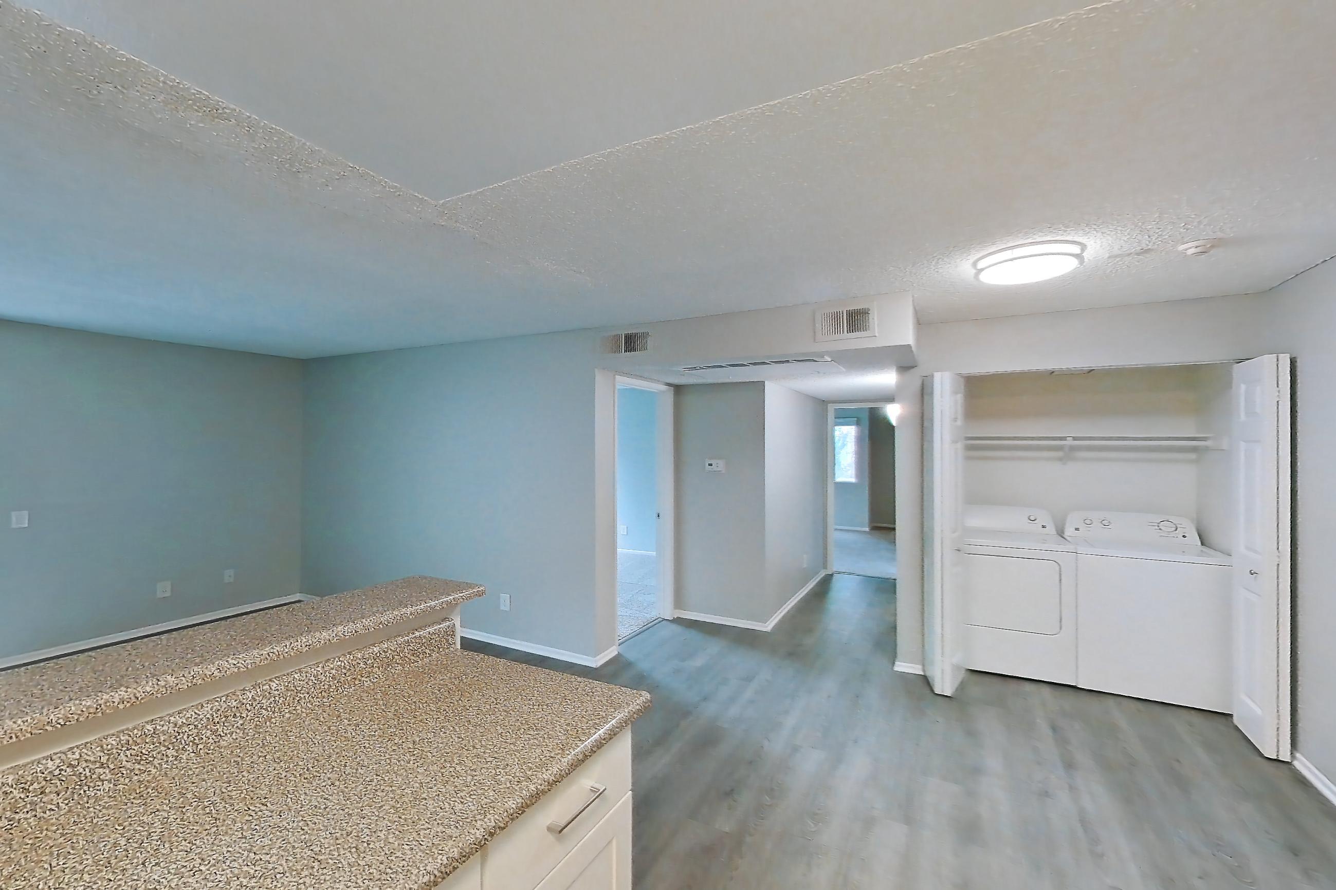 Kitchen with dishwasher, electric range, in-unit laundry, light stone countertops, light wood-finish flooring, oven/range, refrigerator, and stainless steel appliances, Apartment 20-05 at Avana Rancho Cucamonga