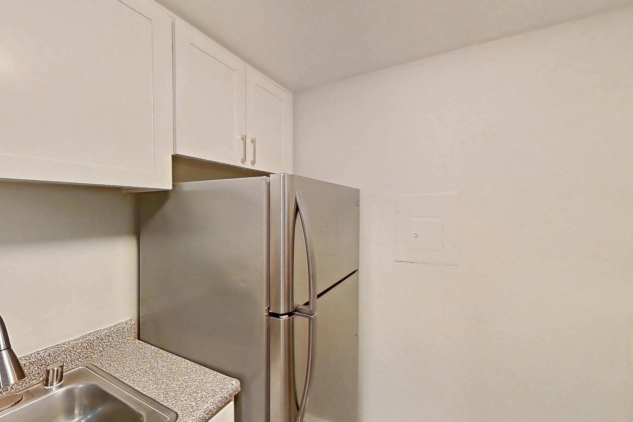 Kitchen with dishwasher, electric range, in-unit laundry, light stone countertops, light wood-finish flooring, oven/range, refrigerator, and stainless steel appliances, Apartment 20-05 at Avana Rancho Cucamonga