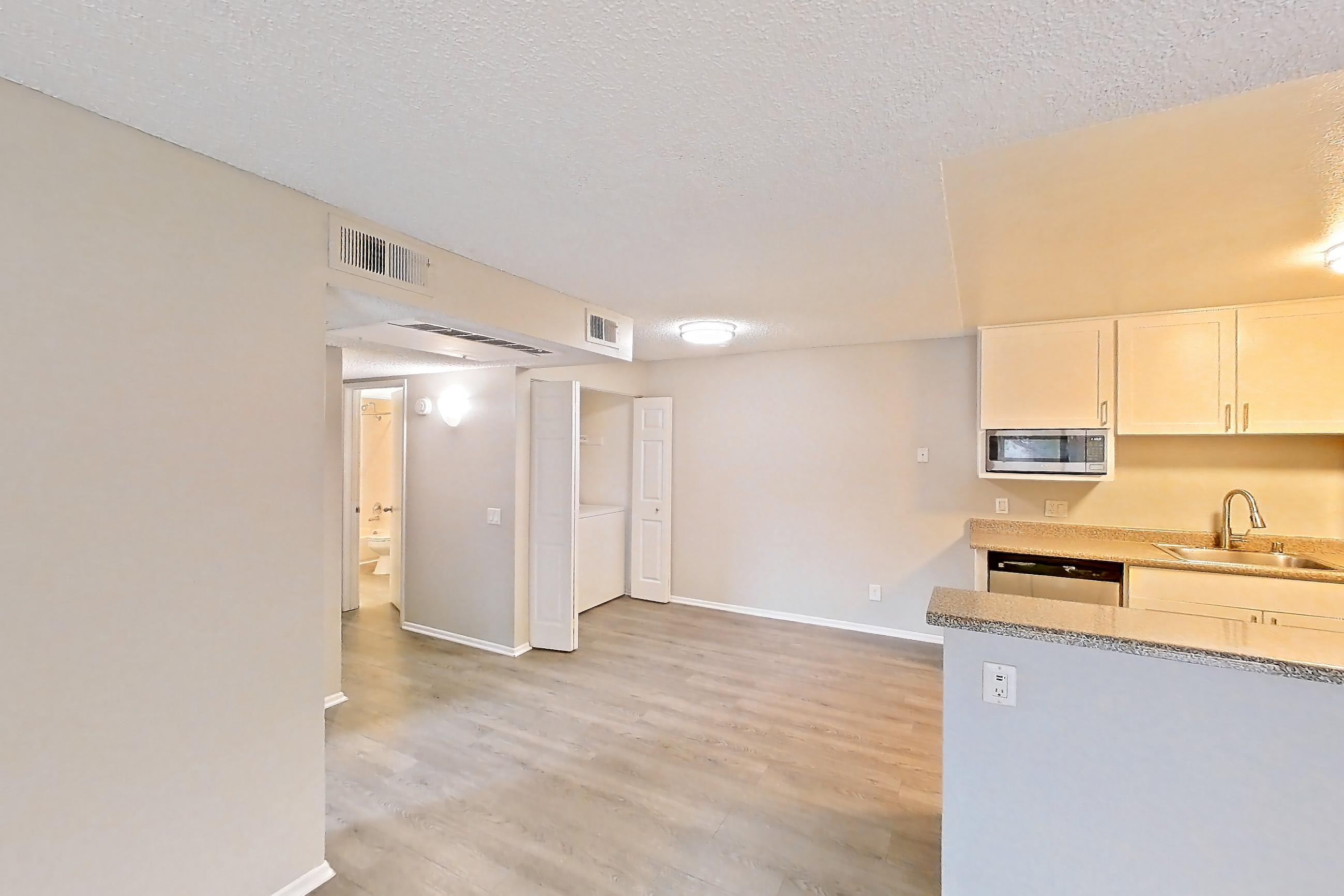 Living room with dark wood-finish flooring, light countertops, refrigerator, and white appliances, Apartment 20-05 at Avana Rancho Cucamonga