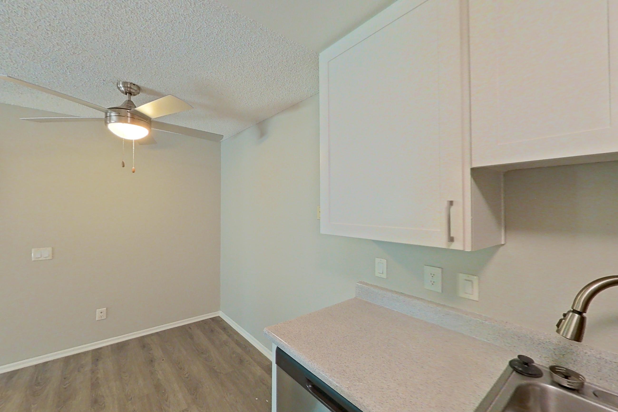 Kitchen with dishwasher, electric range, light countertops, light stone countertops, light wood-finish flooring, microwave, oven/range, refrigerator, and stainless steel appliances, Apartment 02-02 at Avana Rancho Cucamonga