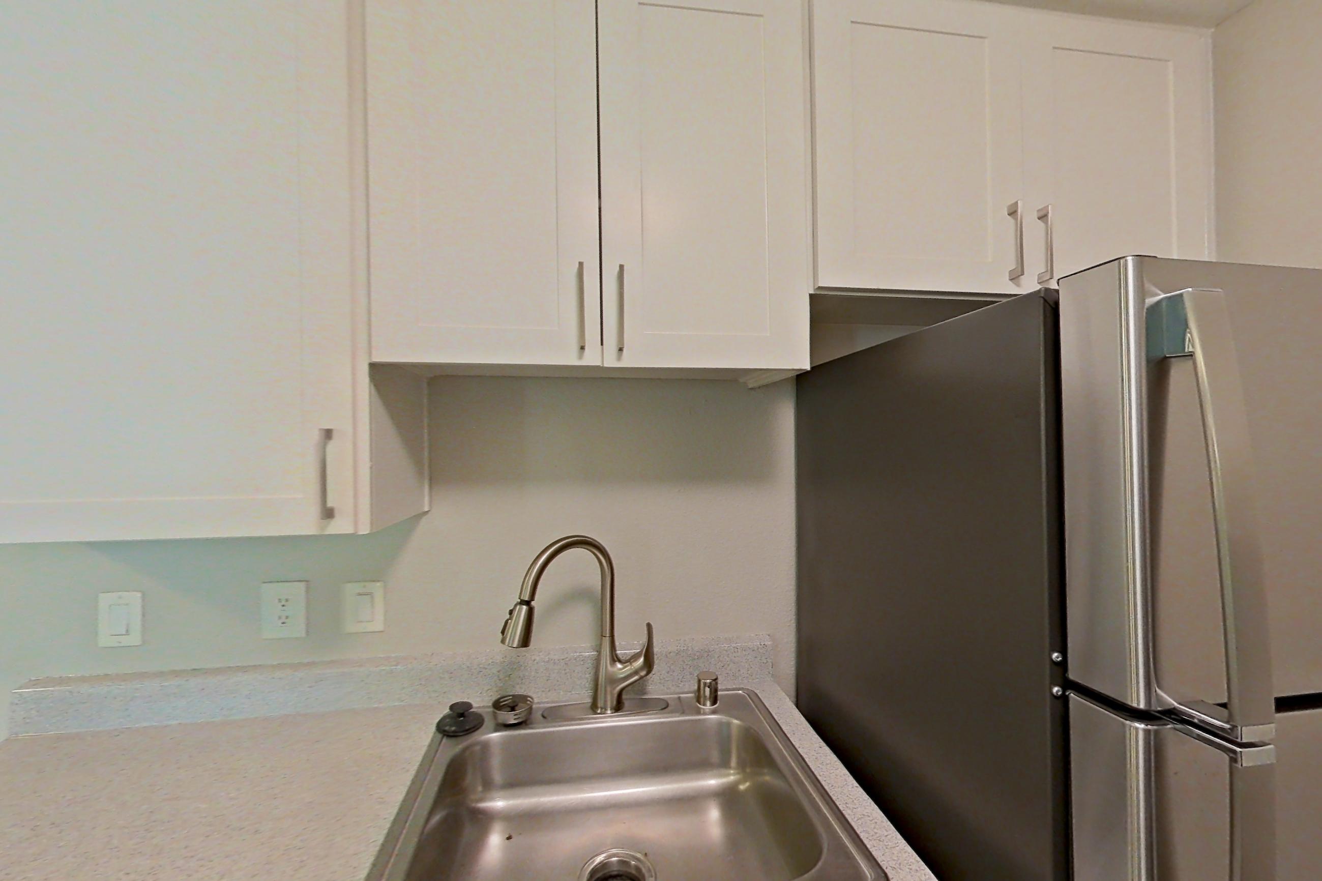 Kitchen with dishwasher, electric range, light countertops, light stone countertops, light wood-finish flooring, microwave, oven/range, refrigerator, and stainless steel appliances, Apartment 02-02 at Avana Rancho Cucamonga