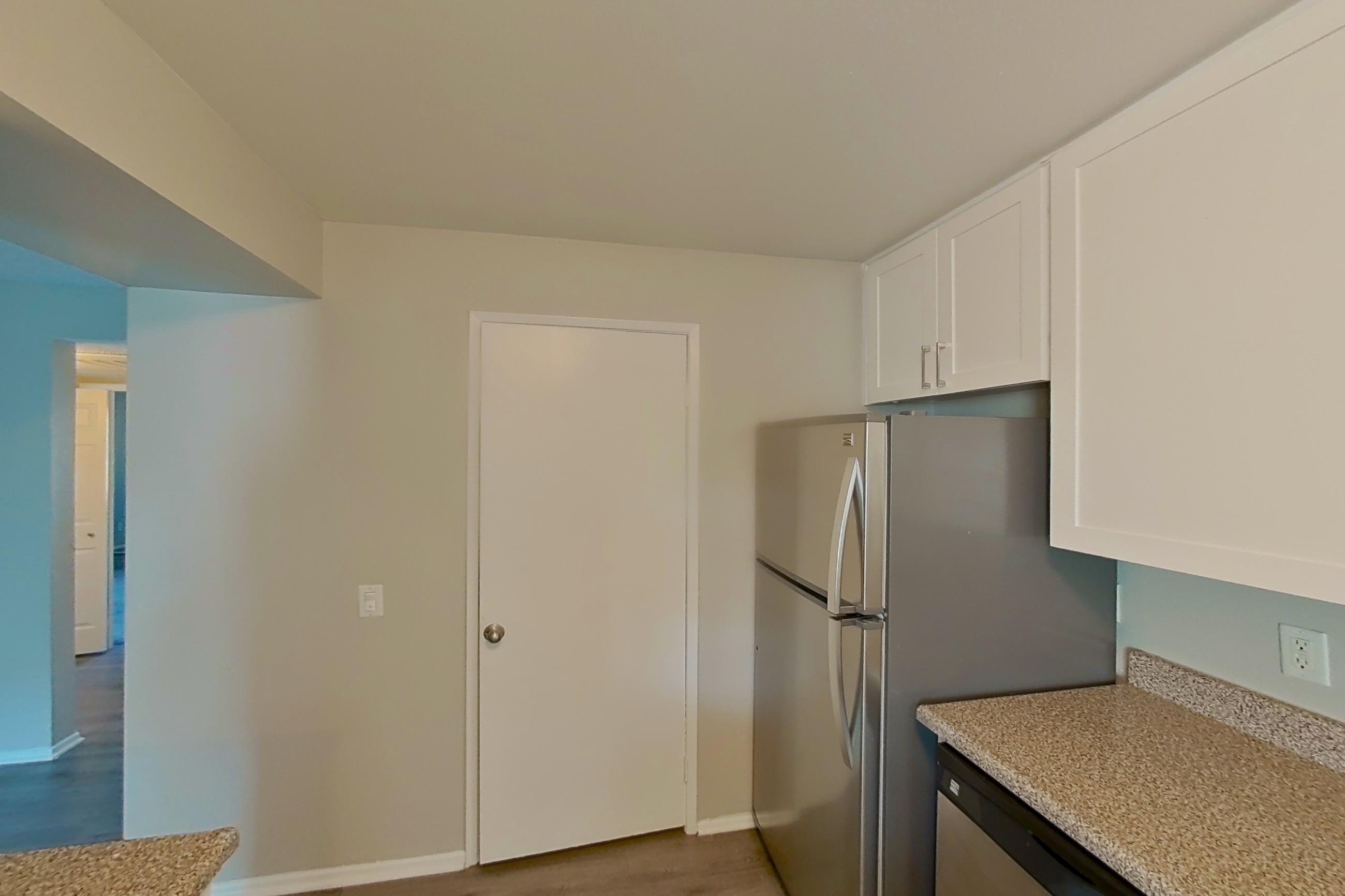Kitchen with black appliances, dishwasher, electric range, light countertops, light stone countertops, light wood-finish flooring, microwave, oven/range, refrigerator, and stainless steel appliances, Apartment 07-03 at Avana Rancho Cucamonga