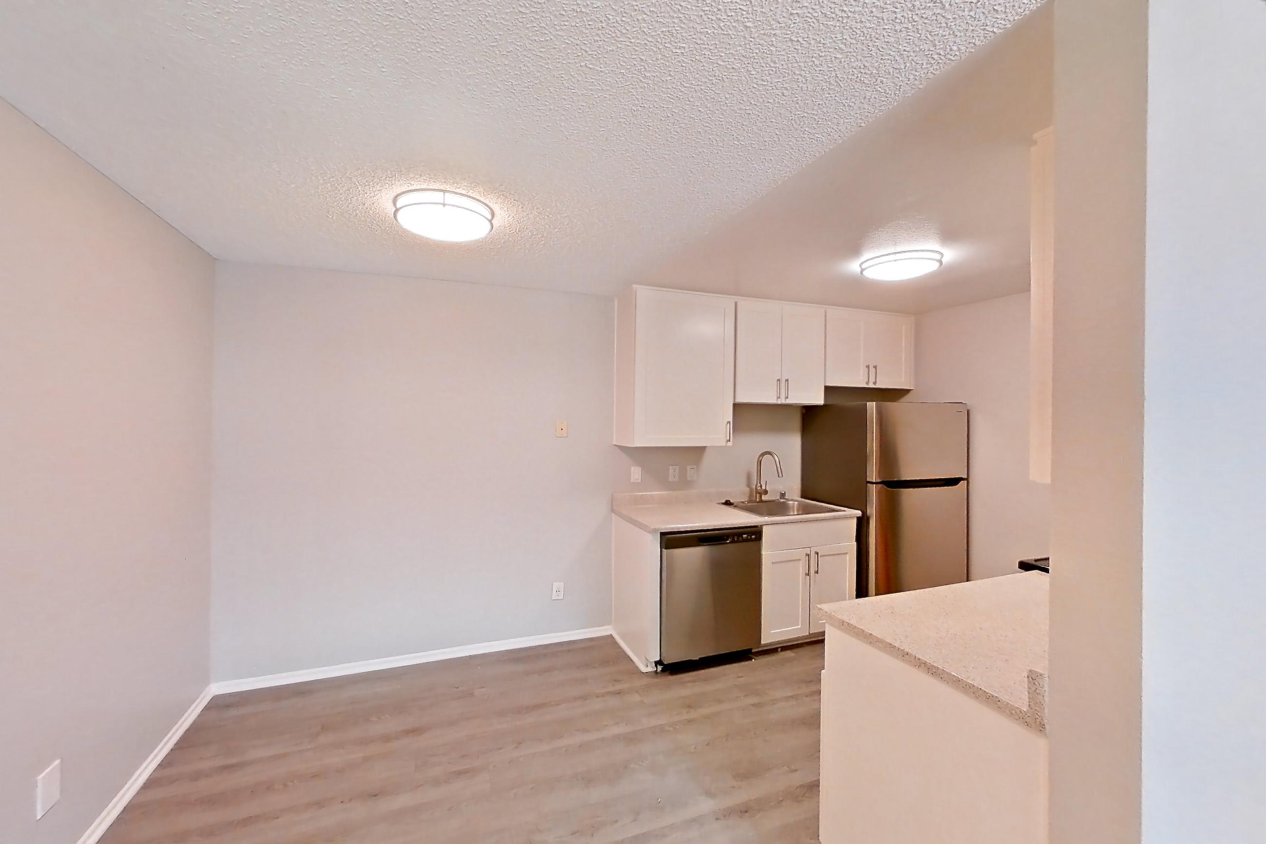Living room with dishwasher, light countertops, light wood-finish flooring, refrigerator, and stainless steel appliances, Apartment 10-06 at Avana Rancho Cucamonga