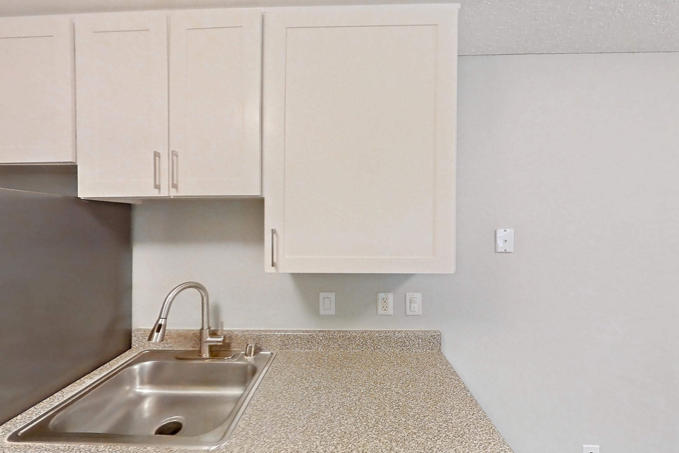 Kitchen with dishwasher, light countertops, light wood-finish flooring, refrigerator, and stainless steel appliances, Apartment 13-08 at Avana Rancho Cucamonga