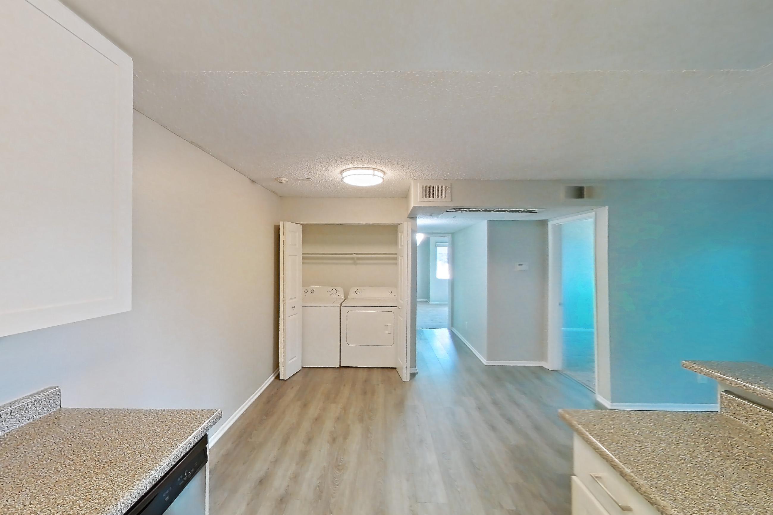 Kitchen with dishwasher, in-unit laundry, light countertops, light stone countertops, light wood-finish flooring, refrigerator, and stainless steel appliances, Apartment 19-10 at Avana Rancho Cucamonga
