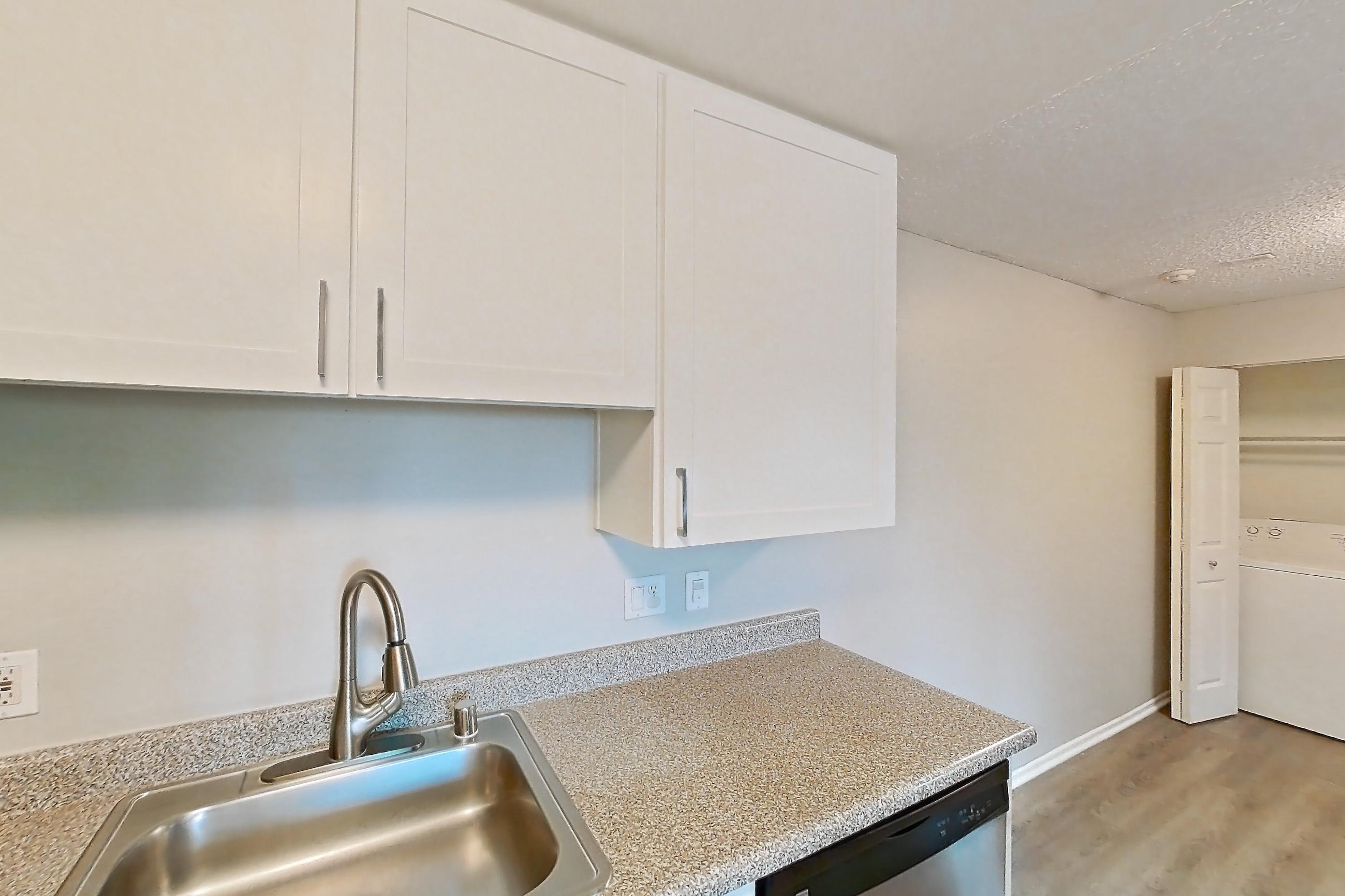 Kitchen with dishwasher, in-unit laundry, light countertops, light stone countertops, light wood-finish flooring, refrigerator, and stainless steel appliances, Apartment 19-10 at Avana Rancho Cucamonga