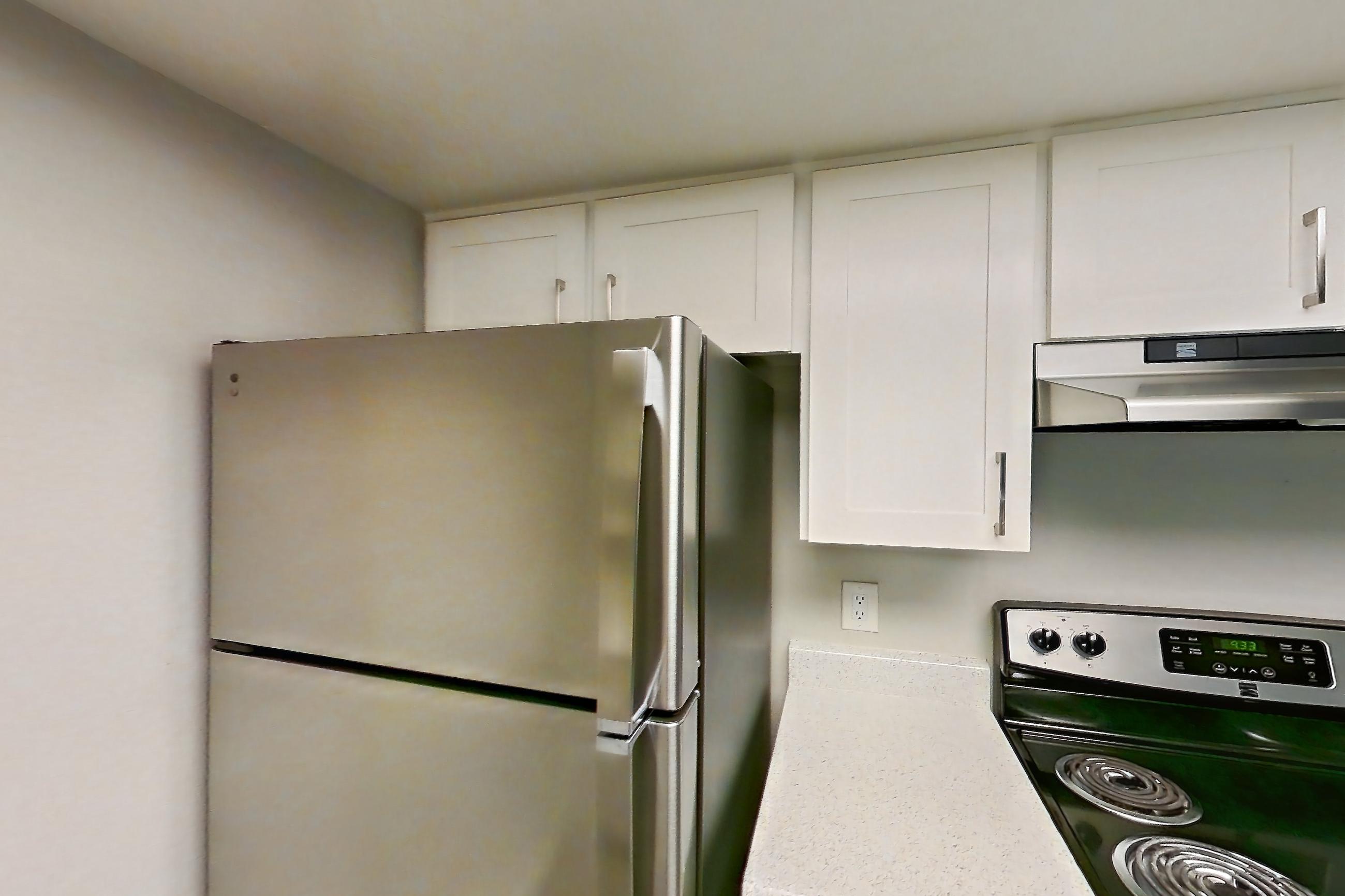 Kitchen with dishwasher, electric range, in-unit laundry, light countertops, light stone countertops, light wood-finish flooring, oven/range, refrigerator, and stainless steel appliances, Apartment 11 at Avana Rancho Cucamonga