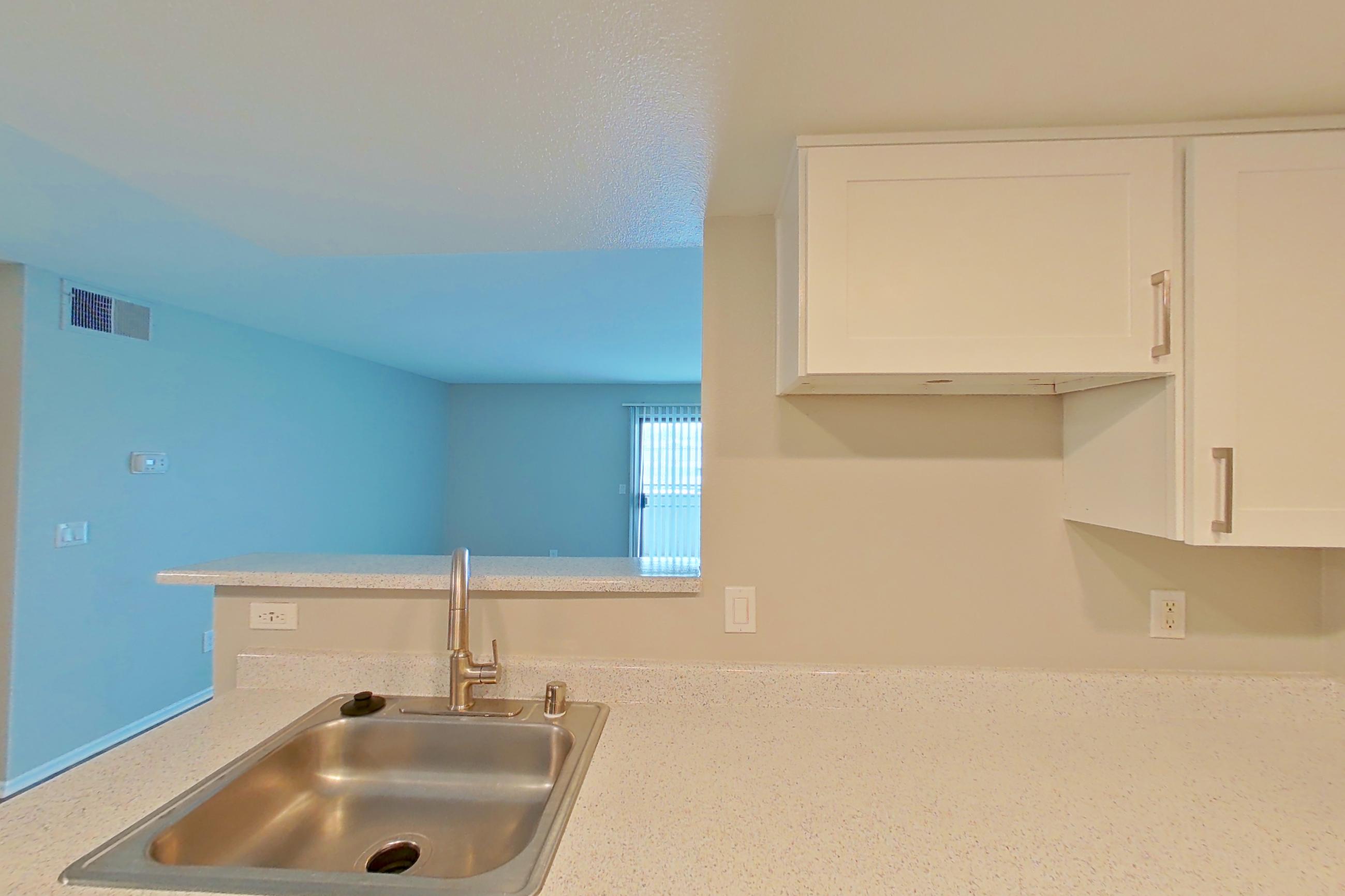 Kitchen with dishwasher, electric range, light countertops, light stone countertops, light wood-finish flooring, microwave, oven/range, refrigerator, stainless steel appliances, and white appliances, Apartment 22 at Avana Rancho Cucamonga