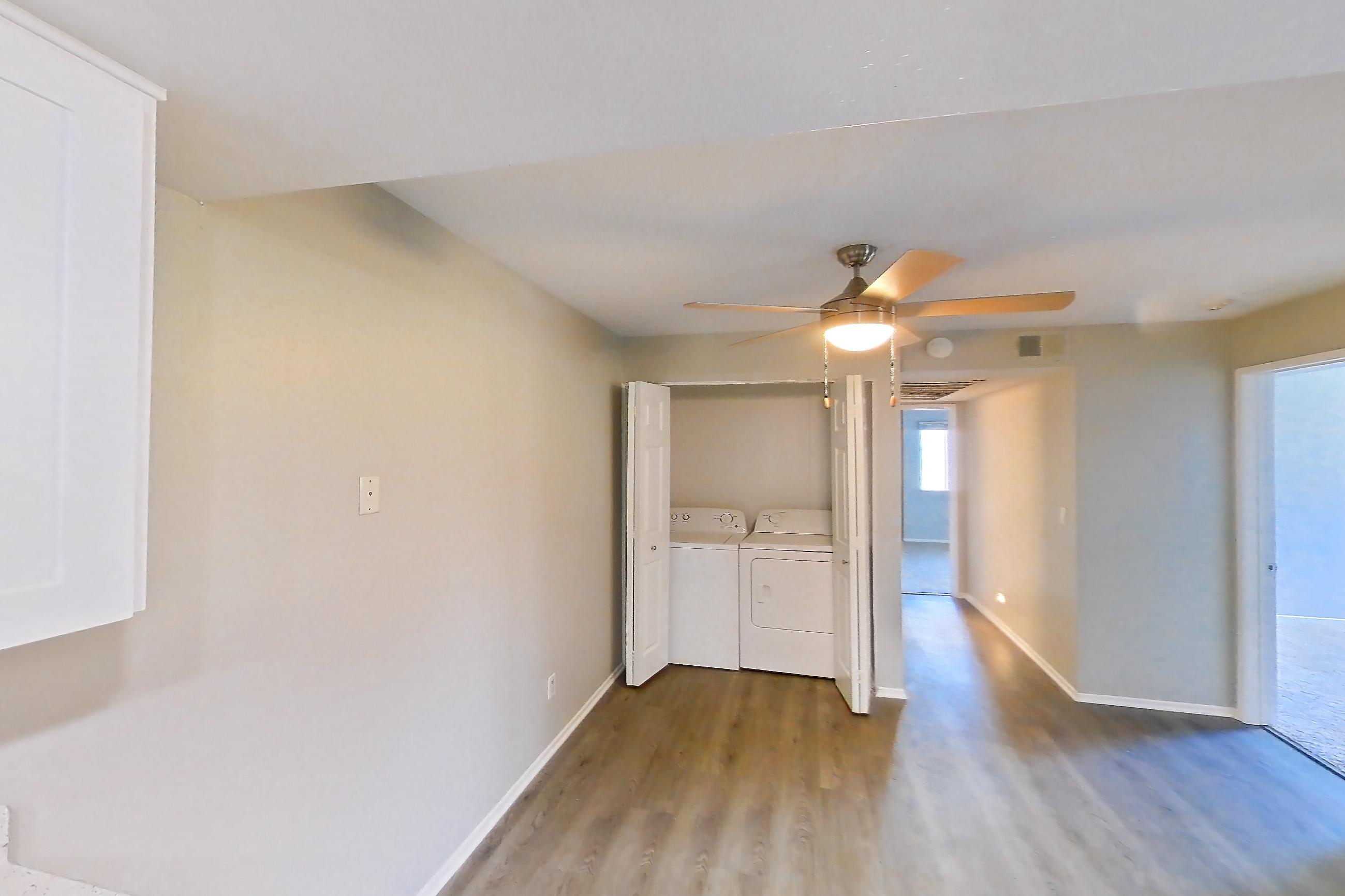 Kitchen with dishwasher, electric range, in-unit laundry, light countertops, light stone countertops, light wood-finish flooring, oven/range, refrigerator, and stainless steel appliances, Apartment 23 at Avana Rancho Cucamonga
