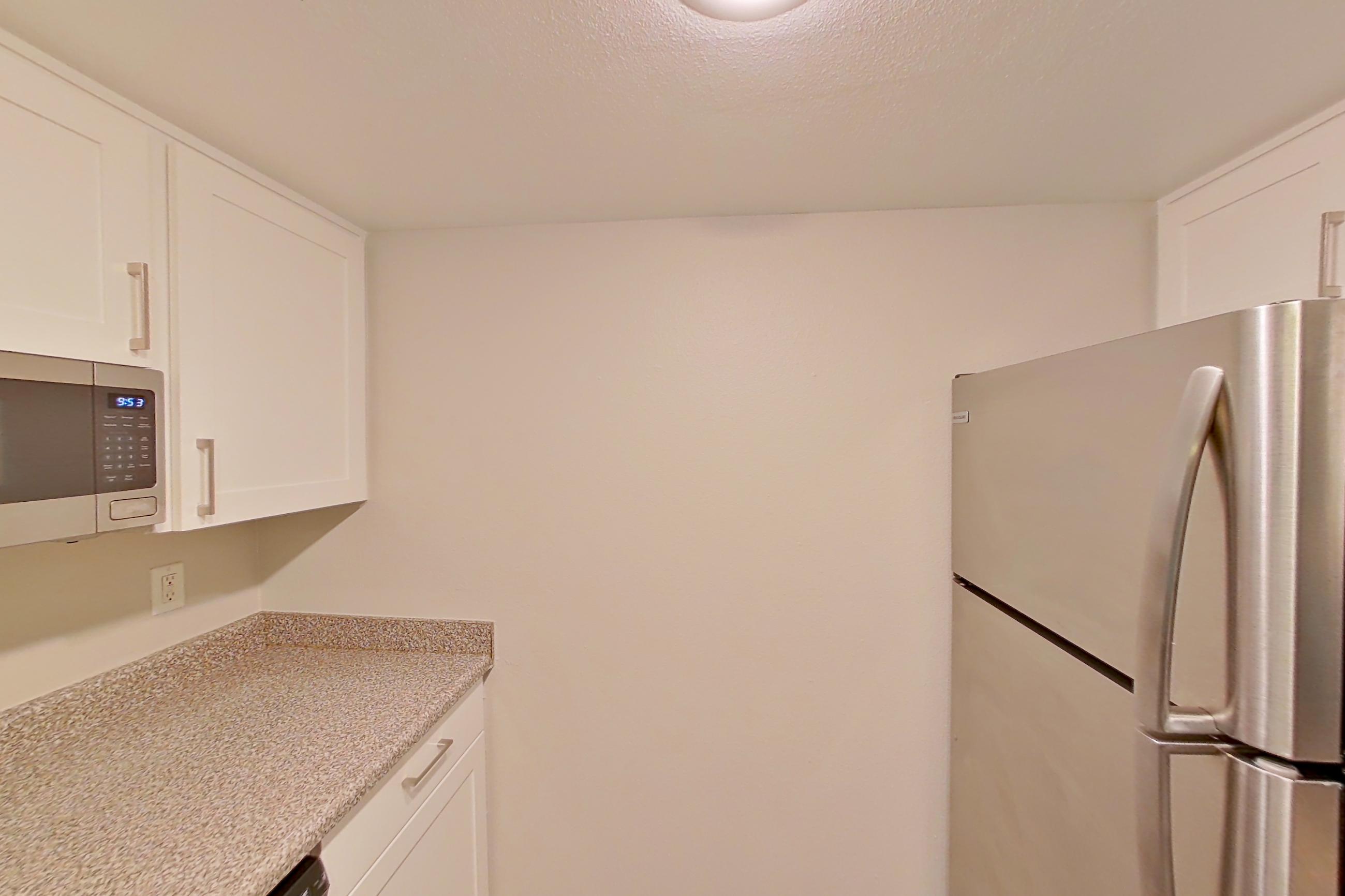 Kitchen with dishwasher, electric range, light countertops, light stone countertops, light wood-finish flooring, oven/range, range hood, refrigerator, and stainless steel appliances, Apartment 11 at Avana Rancho Cucamonga