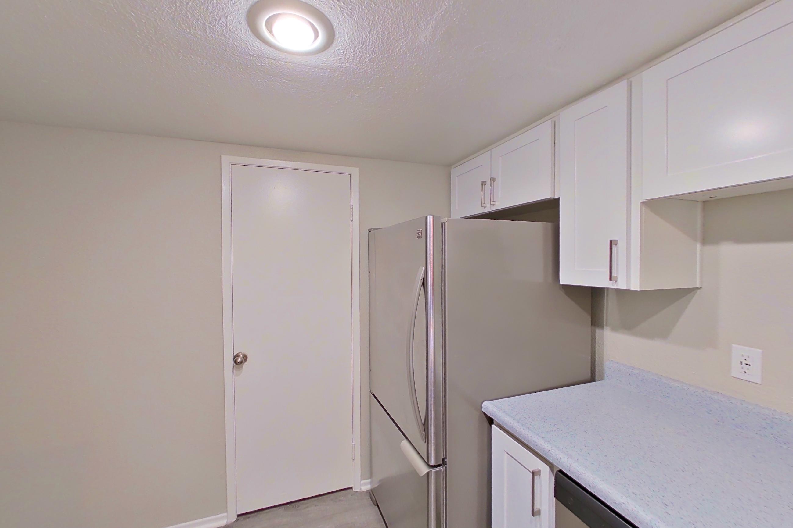 Kitchen with dishwasher, electric range, light countertops, light stone countertops, light wood-finish flooring, microwave, oven/range, refrigerator, and stainless steel appliances, Apartment 12 at Avana Rancho Cucamonga