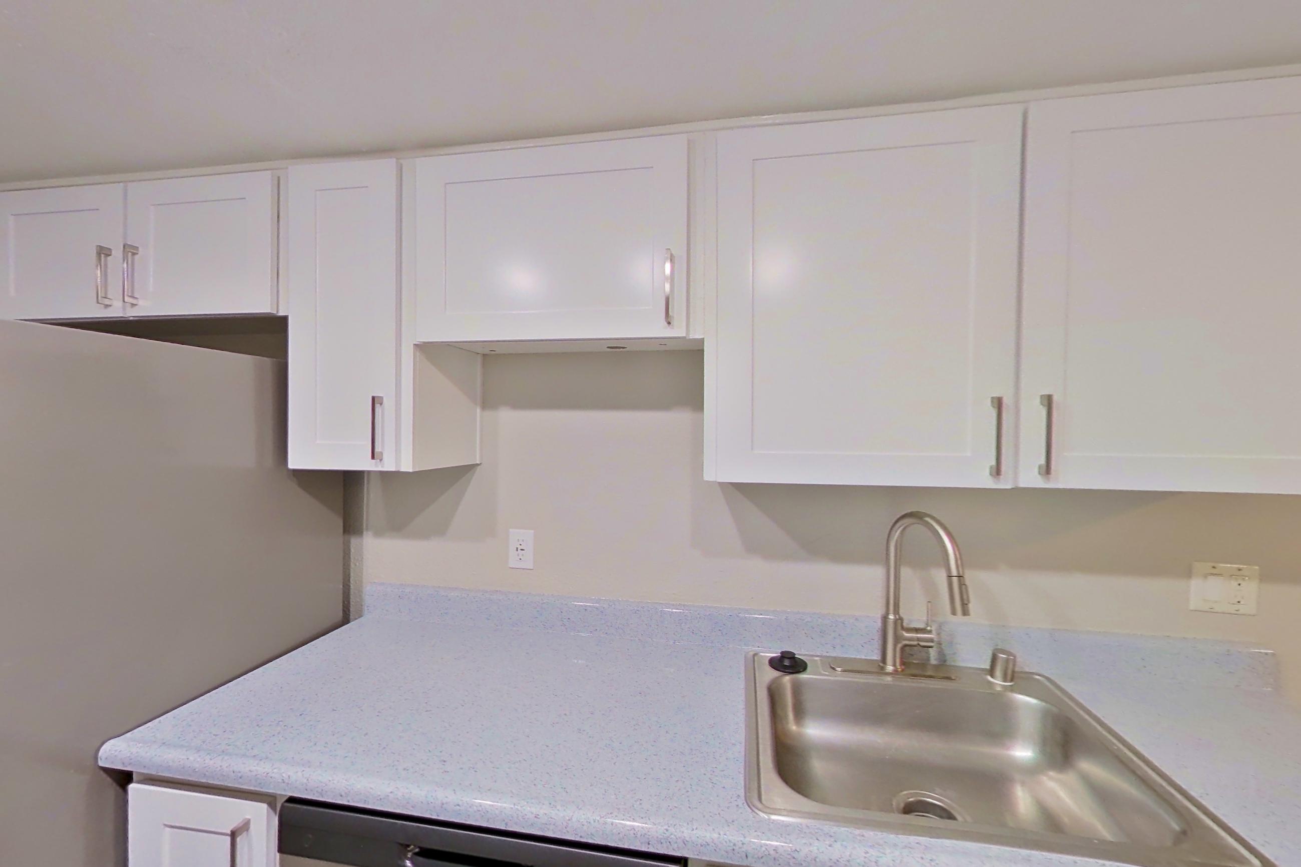 Kitchen with dishwasher, electric range, light countertops, light stone countertops, light wood-finish flooring, microwave, oven/range, refrigerator, and stainless steel appliances, Apartment 12 at Avana Rancho Cucamonga