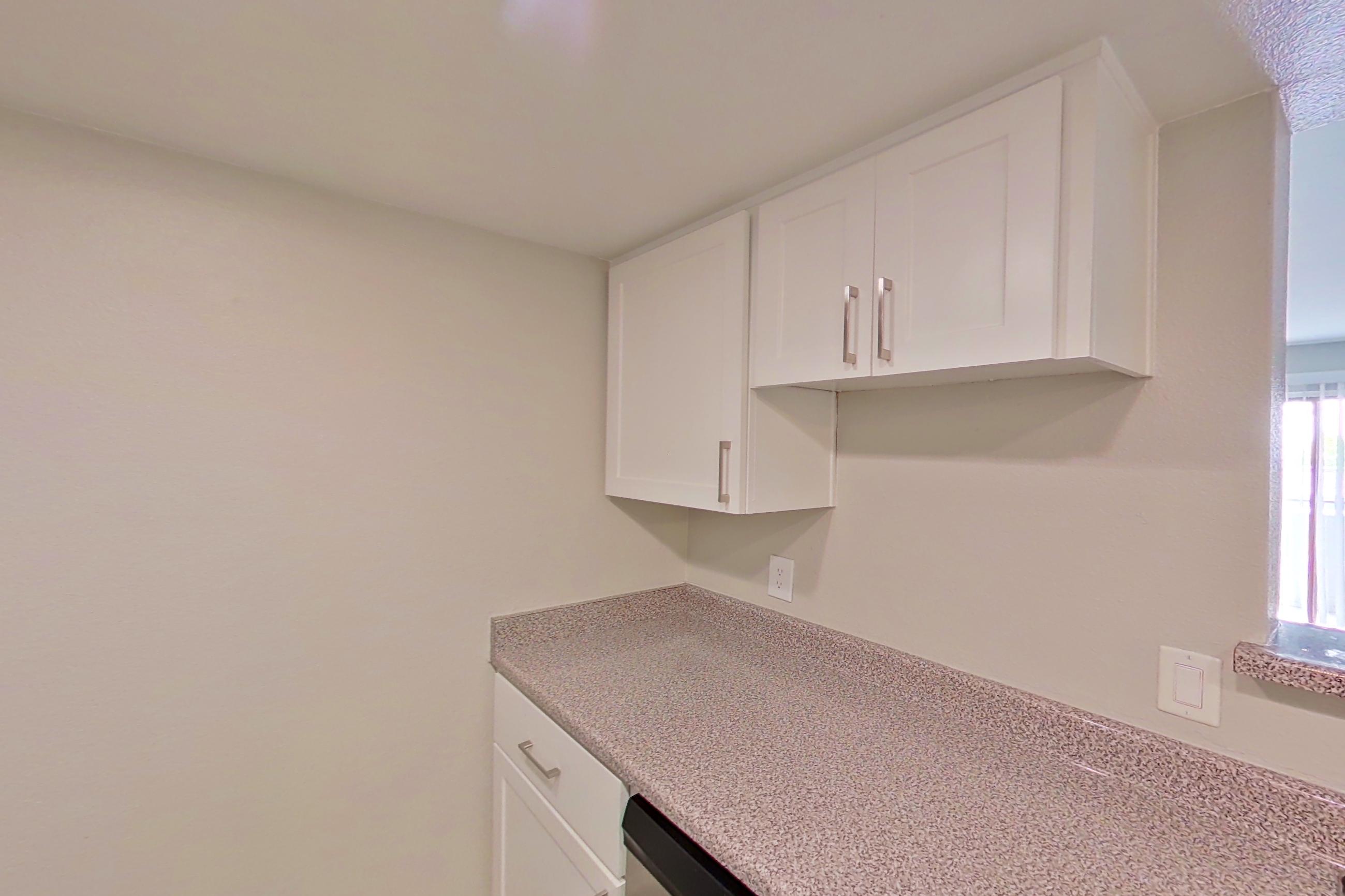 Kitchen with dishwasher, electric range, light countertops, light stone countertops, light wood-finish flooring, oven/range, refrigerator, and stainless steel appliances, Apartment 24 at Avana Rancho Cucamonga