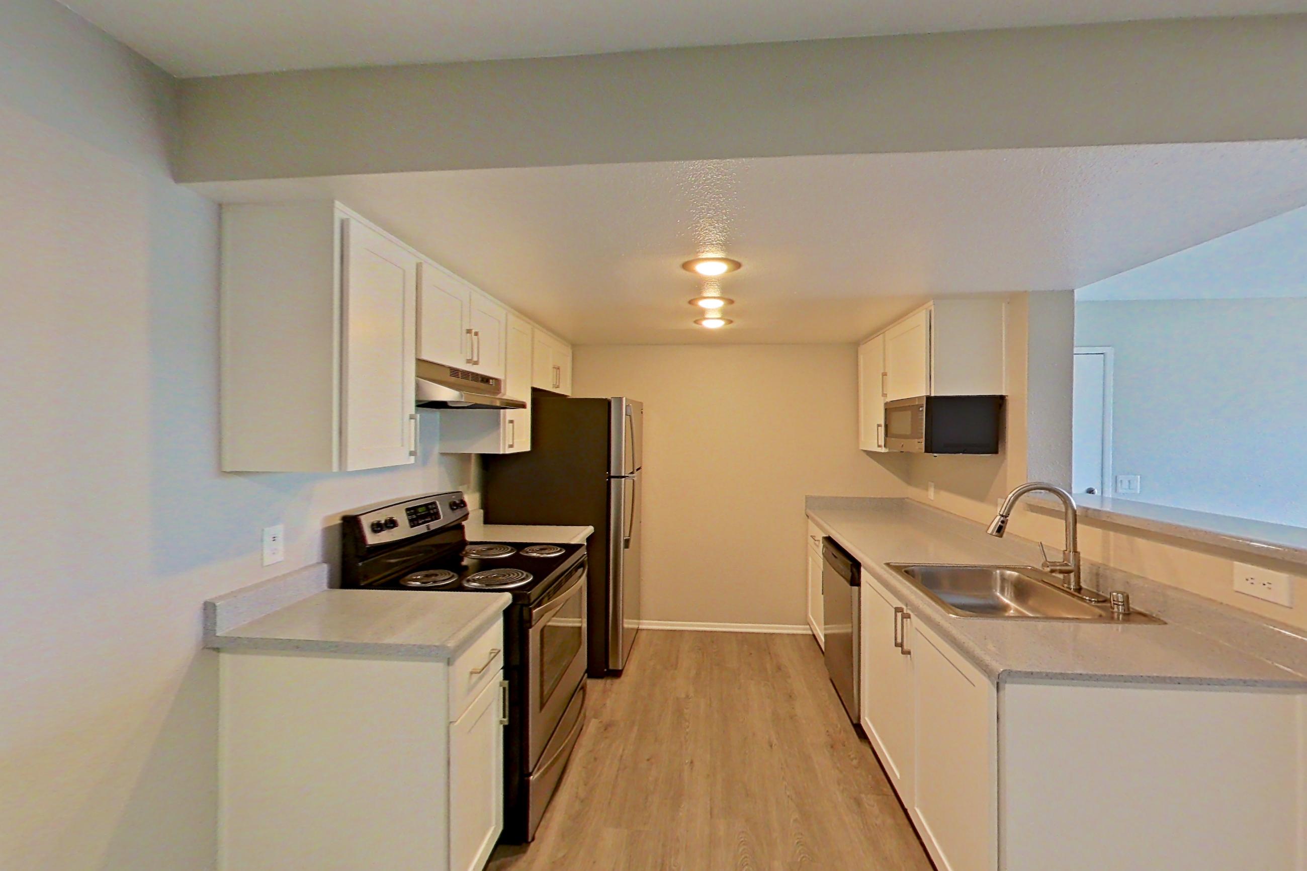 Dining area with dishwasher, electric range, light countertops, light wood-finish flooring, oven/range, refrigerator, and stainless steel appliances, Apartment 20 at Avana Rancho Cucamonga