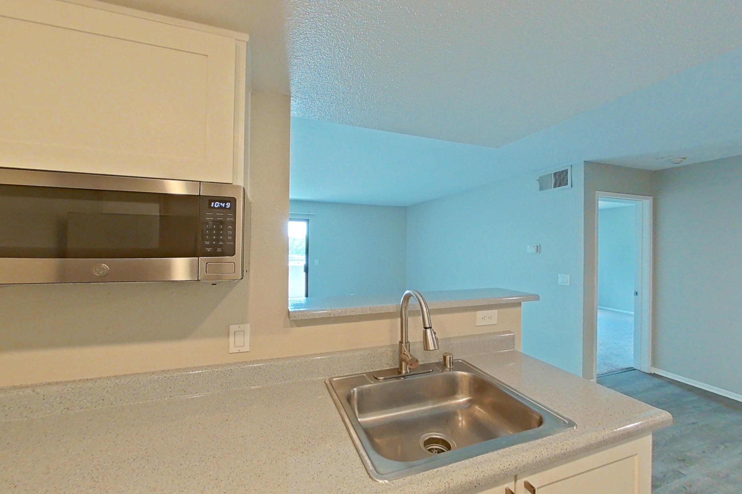 Kitchen with dishwasher, electric range, light countertops, light wood-finish flooring, microwave, oven/range, and stainless steel appliances, Apartment 20 at Avana Rancho Cucamonga