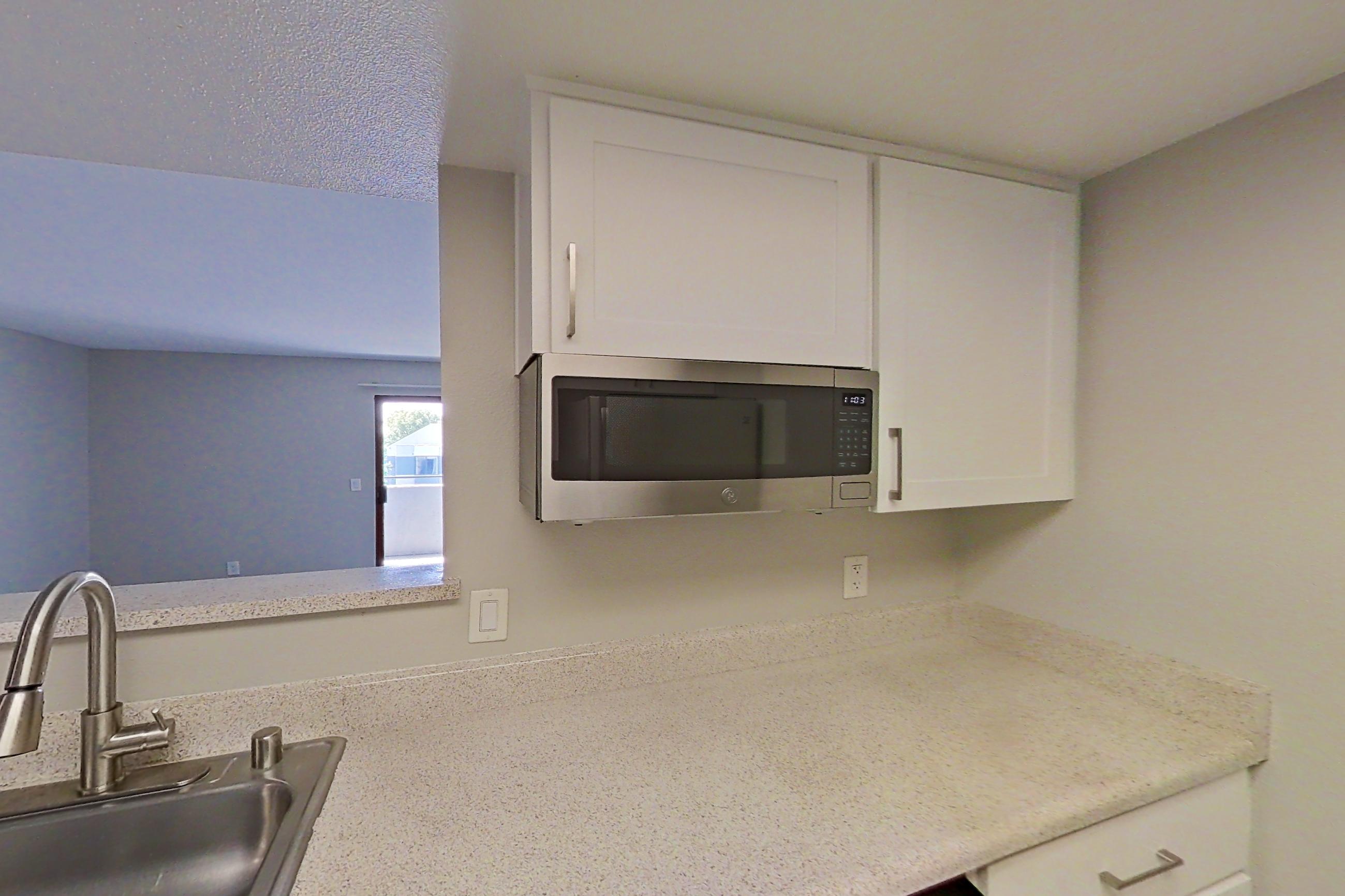 Kitchen with dishwasher, electric range, light countertops, light wood-finish flooring, microwave, oven/range, range hood, refrigerator, and stainless steel appliances, Apartment 10 at Avana Rancho Cucamonga