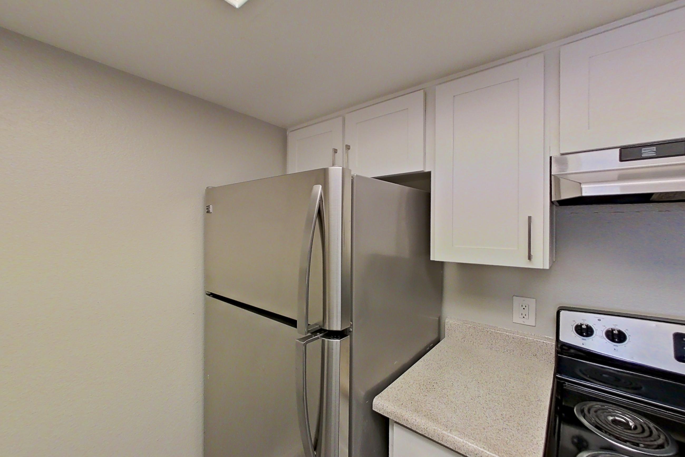 Kitchen with dishwasher, electric range, light countertops, light wood-finish flooring, microwave, oven/range, range hood, refrigerator, and stainless steel appliances, Apartment 10 at Avana Rancho Cucamonga