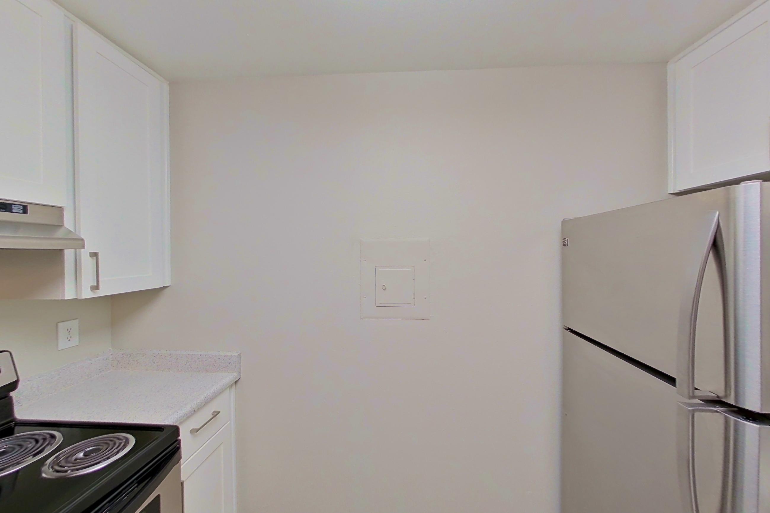 Kitchen with dishwasher, electric range, light countertops, light stone countertops, light wood-finish flooring, oven/range, range hood, refrigerator, and stainless steel appliances, Apartment 16-14 at Avana Rancho Cucamonga