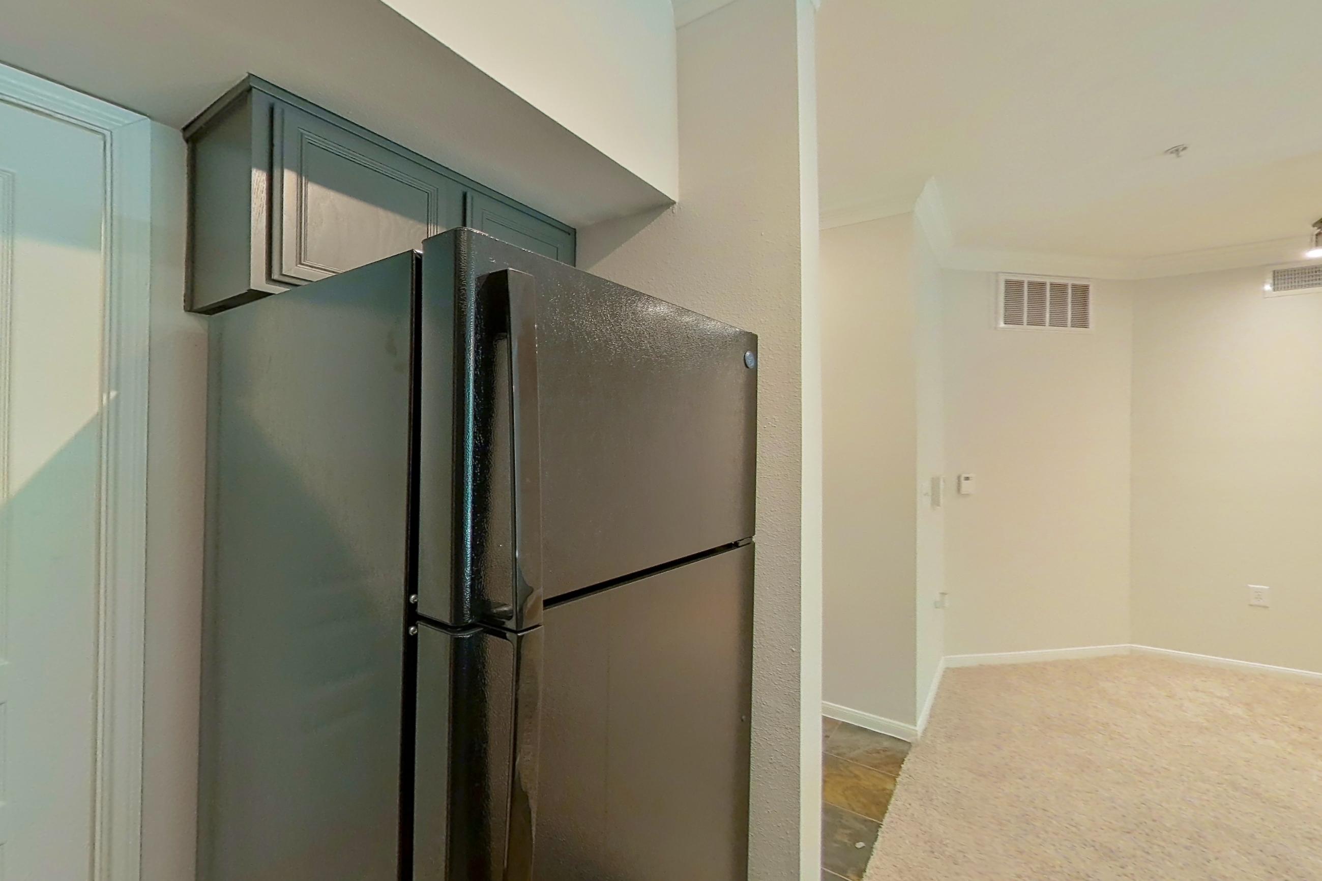 Kitchen with black appliances, dark stone-finish flooring, dishwasher, electric range, light stone countertops, microwave, oven/range, refrigerator, and stainless steel appliances, Apartment 0234 at Portico Kirby