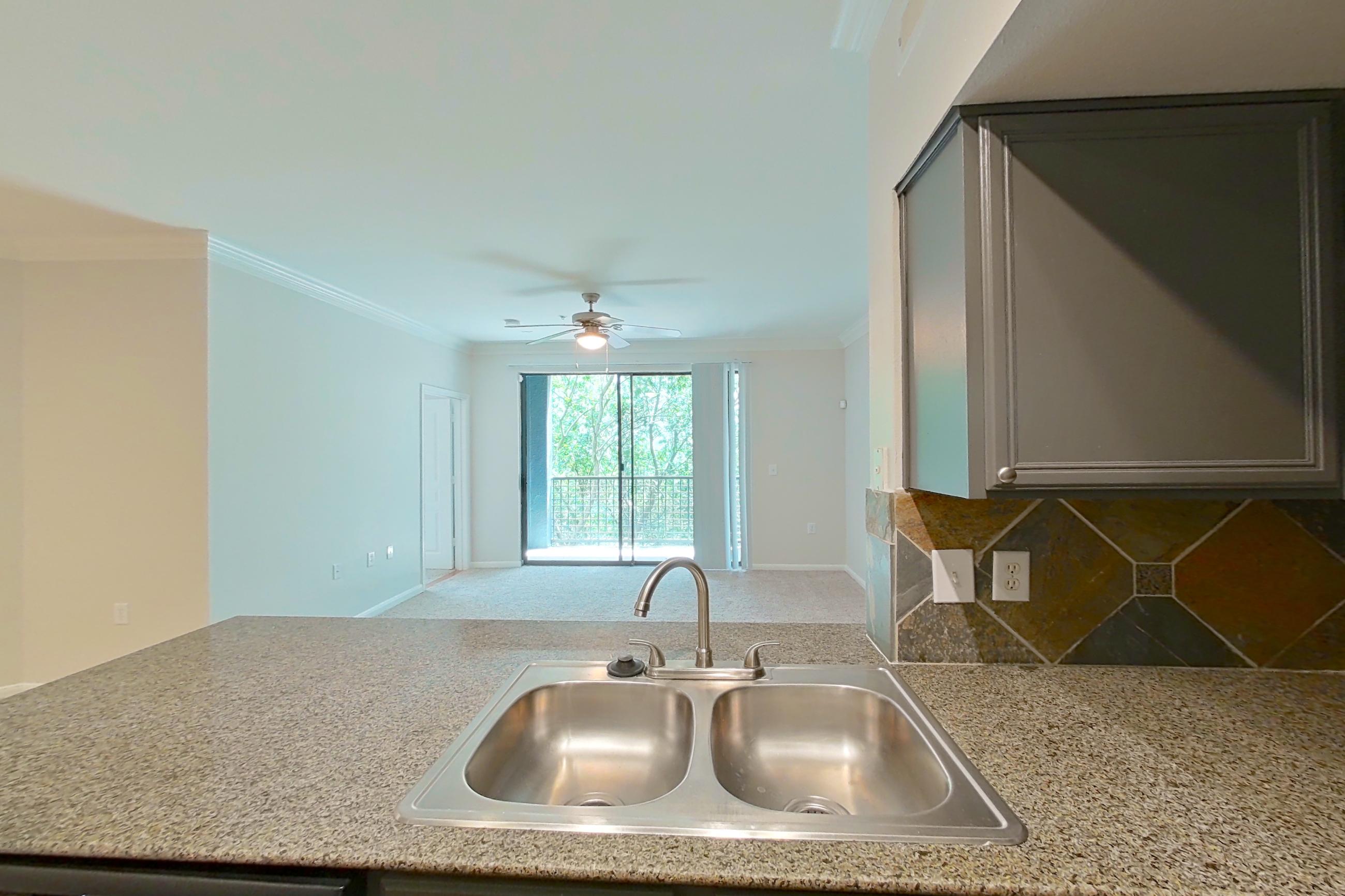 Kitchen with black appliances, dark stone-finish flooring, dishwasher, electric range, light stone countertops, microwave, oven/range, refrigerator, and stainless steel appliances, Apartment 0234 at Portico Kirby