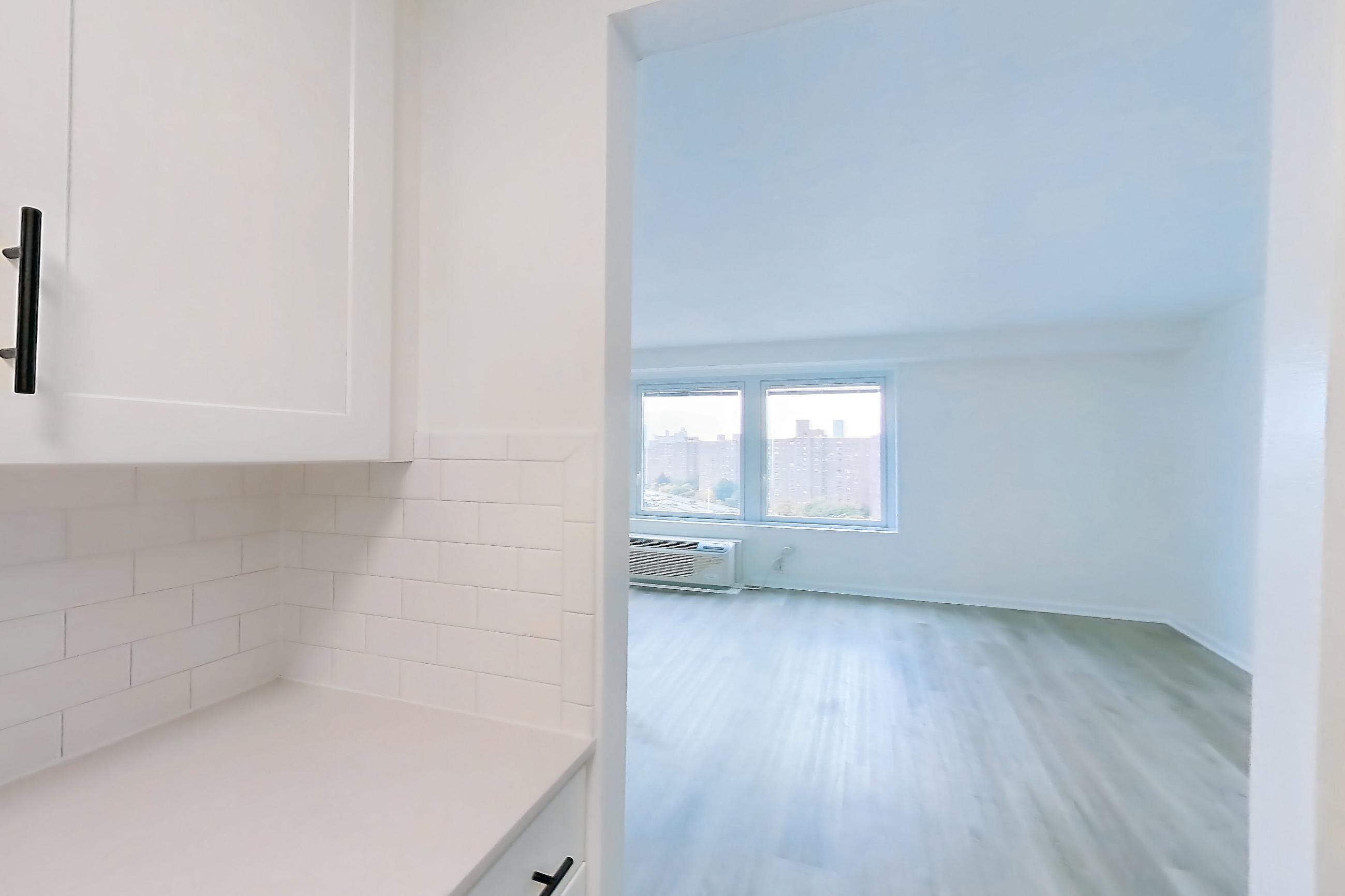 Kitchen with air conditioning, dishwasher, gas range, light countertops, light stone countertops, light wood-finish flooring, microwave, oven/range, and stainless steel appliances, Apartment 10-11K at Waterside Plaza