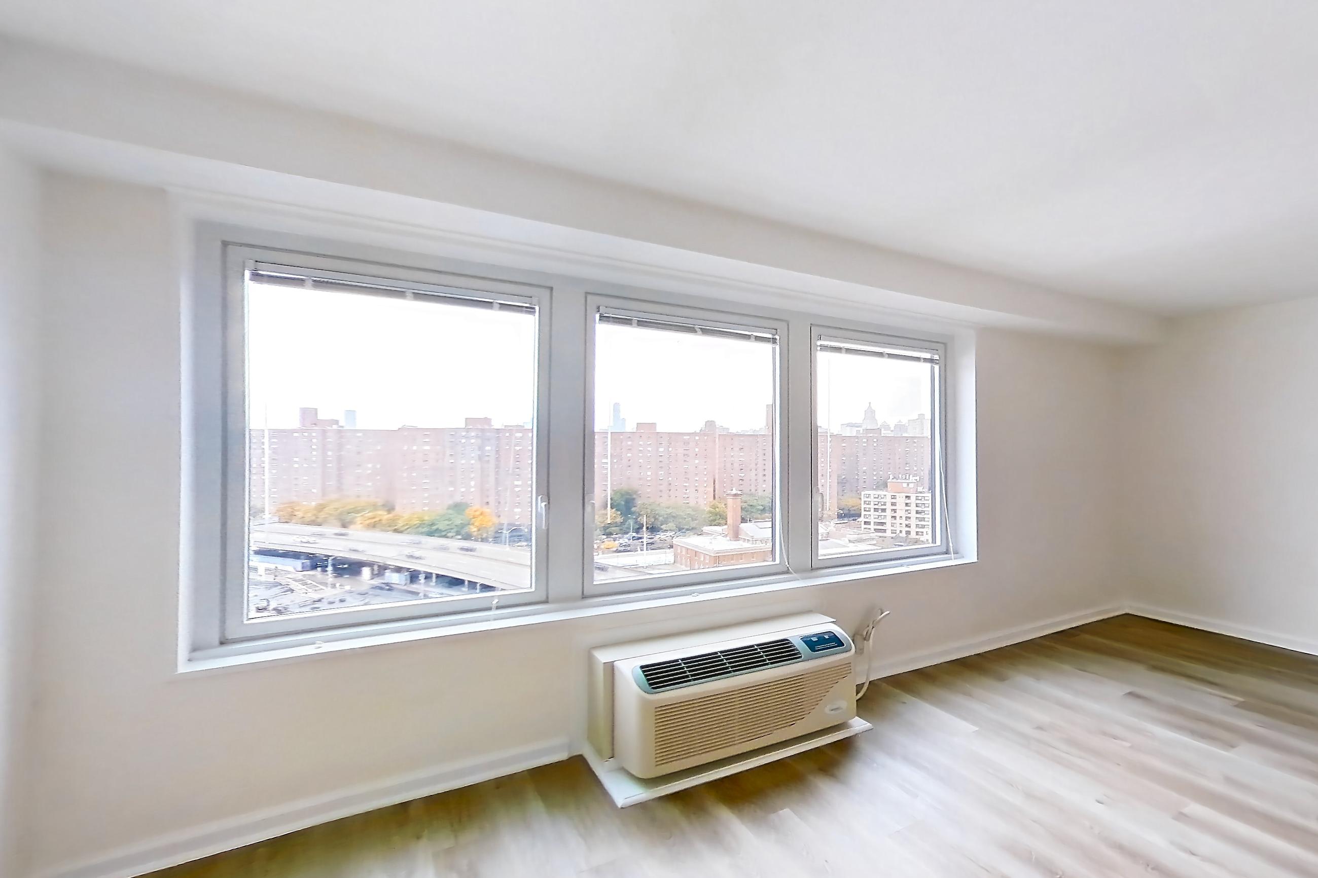 Living room with air conditioning and light wood-finish flooring, Apartment 10-11K at Waterside Plaza
