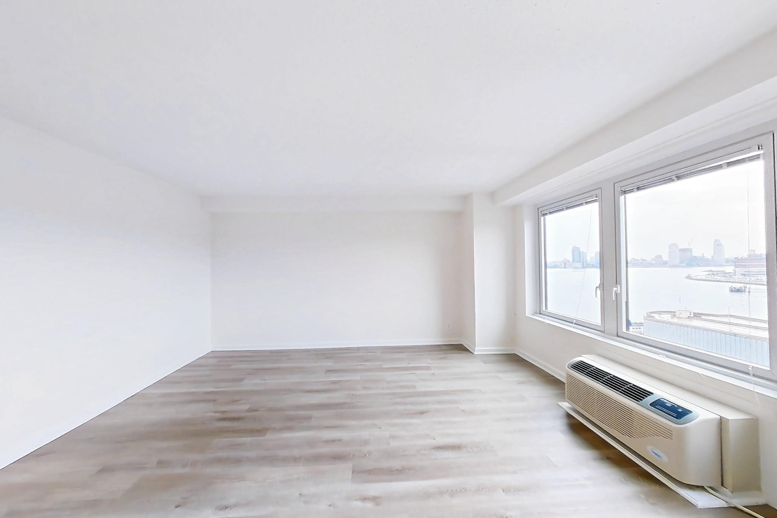 Living space with air conditioning, dishwasher, light wood-finish flooring, refrigerator, and stainless steel appliances, Apartment 10-11K at Waterside Plaza