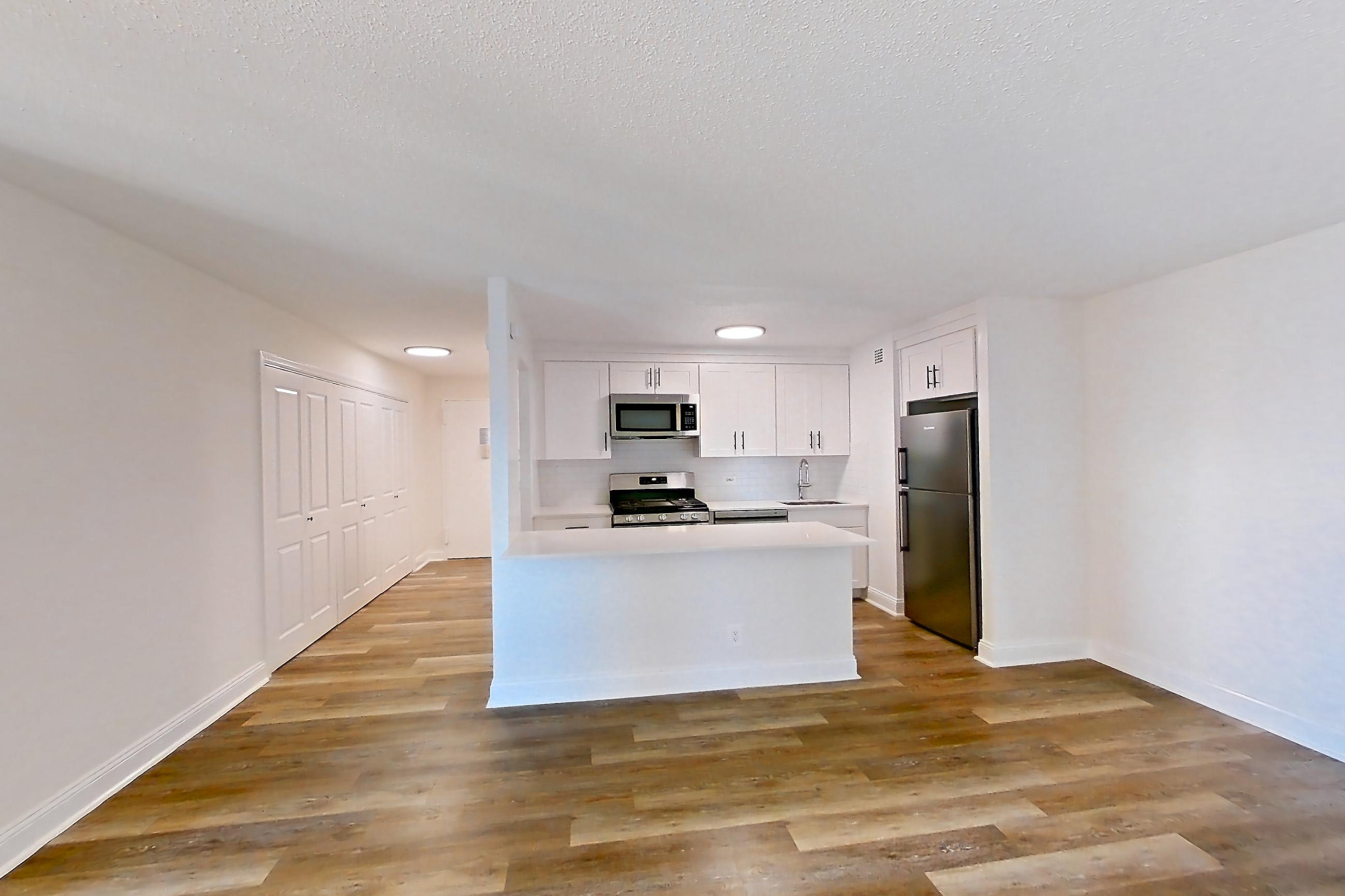 Living space with air conditioning, gas range, light countertops, microwave, oven/range, refrigerator, and stainless steel appliances, Apartment 10-14H at Waterside Plaza