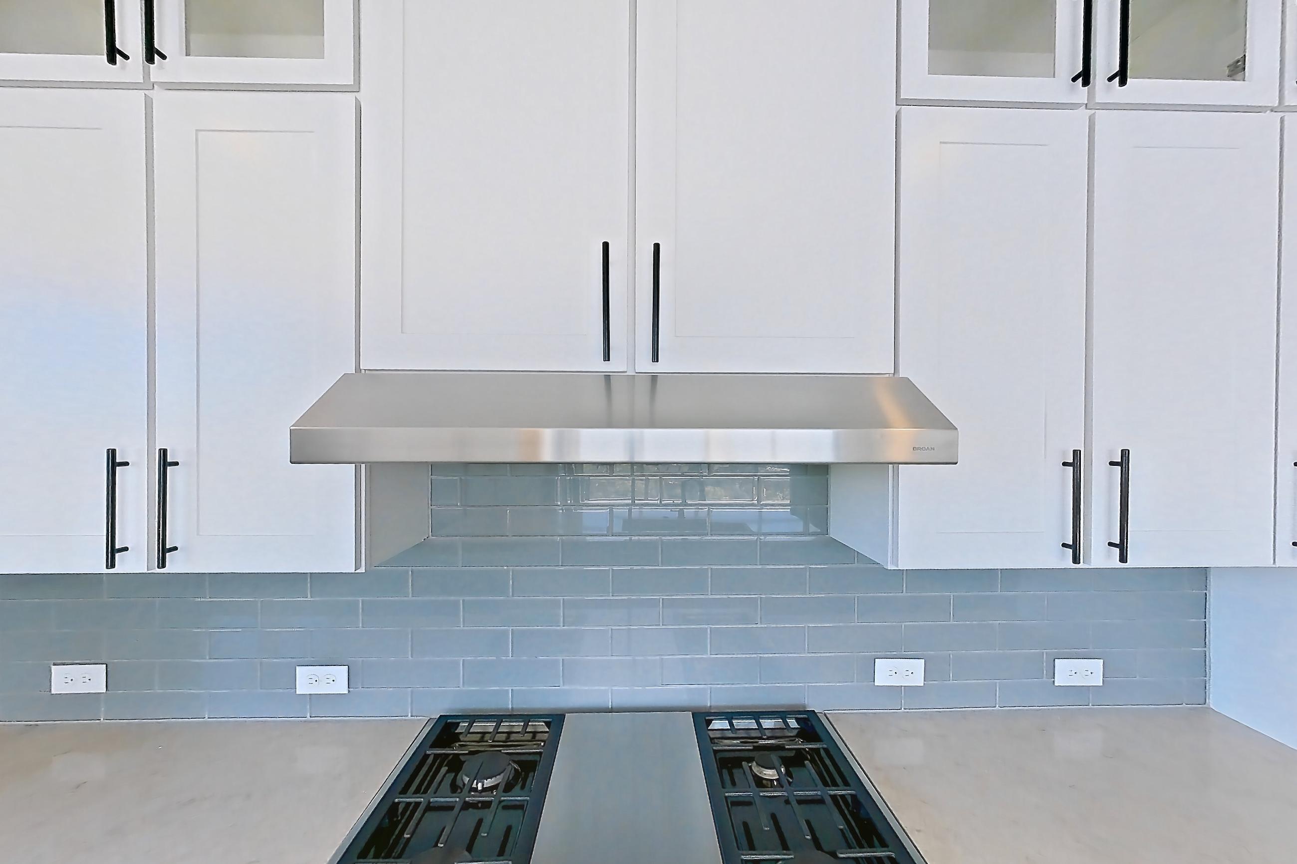 Kitchen with cooktop, dishwasher, double oven, gas cooktop, gas range, light countertops, light stone countertops, light wood-finish flooring, oven/range, refrigerator, stainless steel appliances, and water & ice dispenser, Apartment 1111 at Parq on Speer