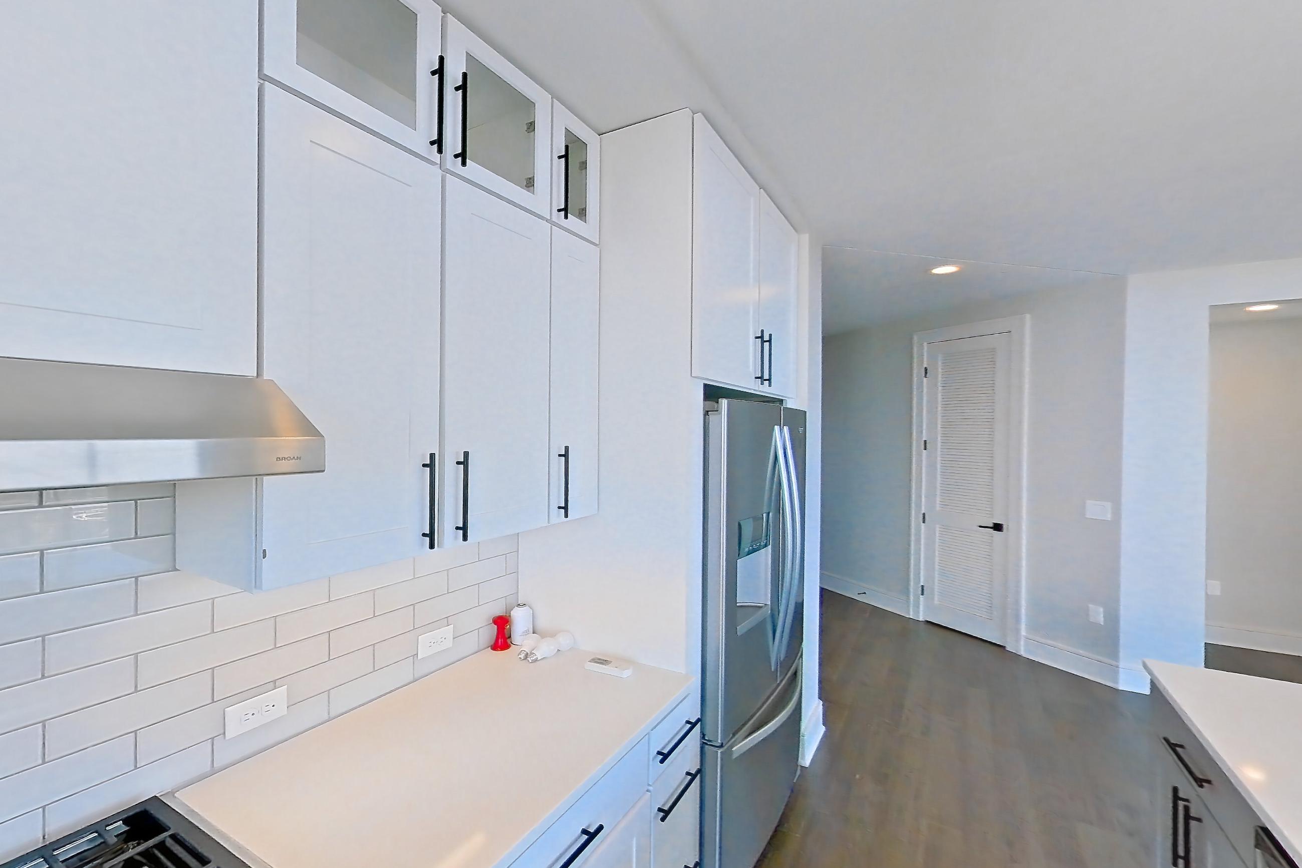 Kitchen with cooktop, dark wood-finish flooring, dishwasher, double oven, gas cooktop, gas range, light countertops, light stone countertops, oven/range, refrigerator, stainless steel appliances, and water & ice dispenser, Apartment 1411 at Parq on Speer