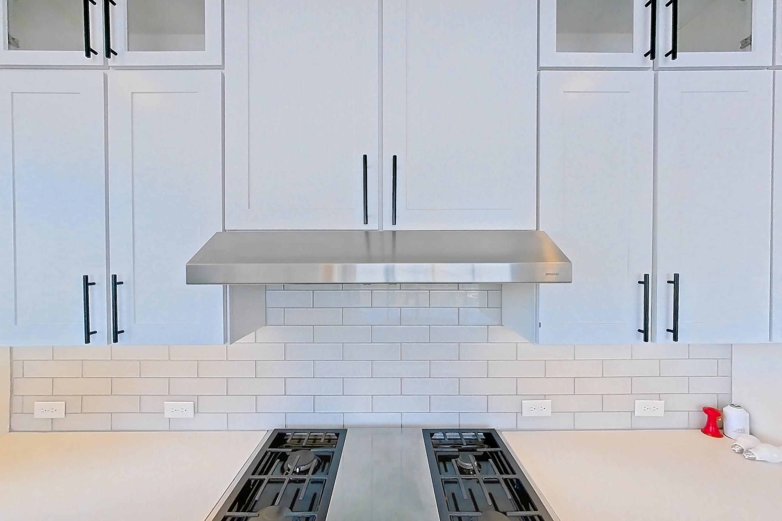 Kitchen with cooktop, dark wood-finish flooring, dishwasher, double oven, gas cooktop, gas range, light countertops, light stone countertops, oven/range, refrigerator, stainless steel appliances, and water & ice dispenser, Apartment 1411 at Parq on Speer