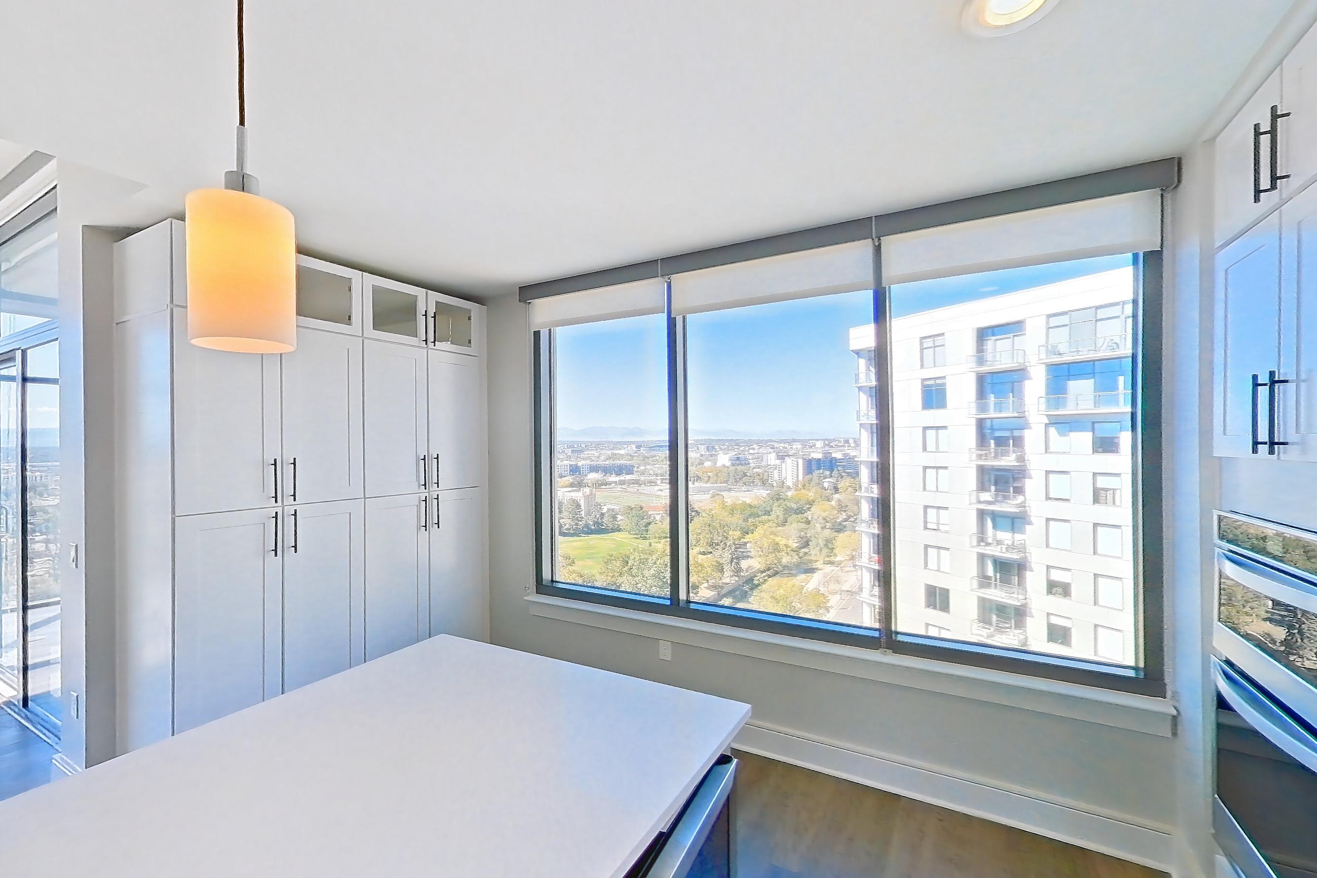 Kitchen with cooktop, dark wood-finish flooring, dishwasher, double oven, gas cooktop, gas range, light countertops, light stone countertops, oven/range, refrigerator, stainless steel appliances, and water & ice dispenser, Apartment 1411 at Parq on Speer