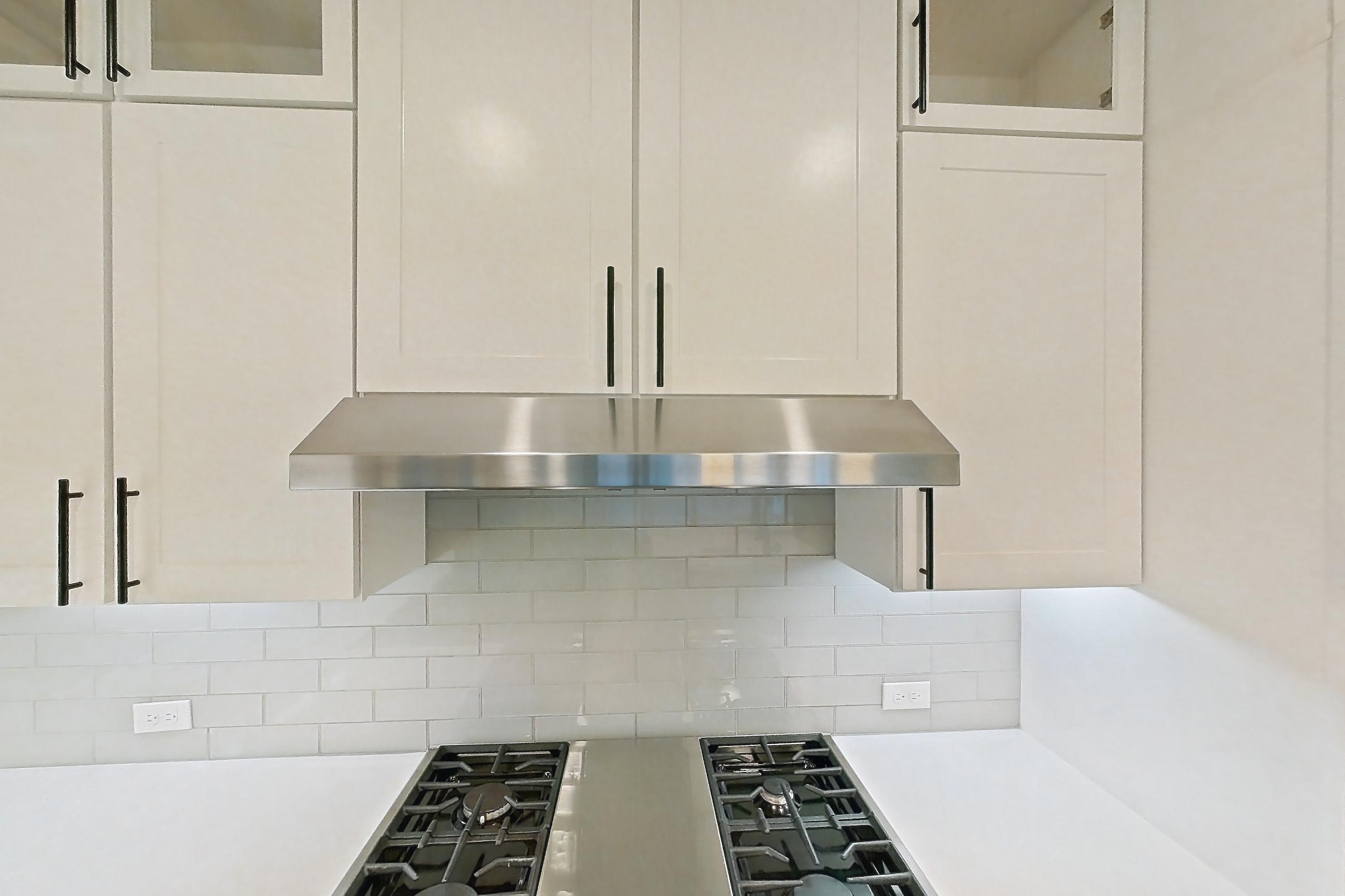 Kitchen with cooktop, dark wood-finish flooring, dishwasher, double oven, gas cooktop, gas range, light countertops, light stone countertops, oven/range, refrigerator, stainless steel appliances, and water & ice dispenser, Apartment 828 at Parq on Speer