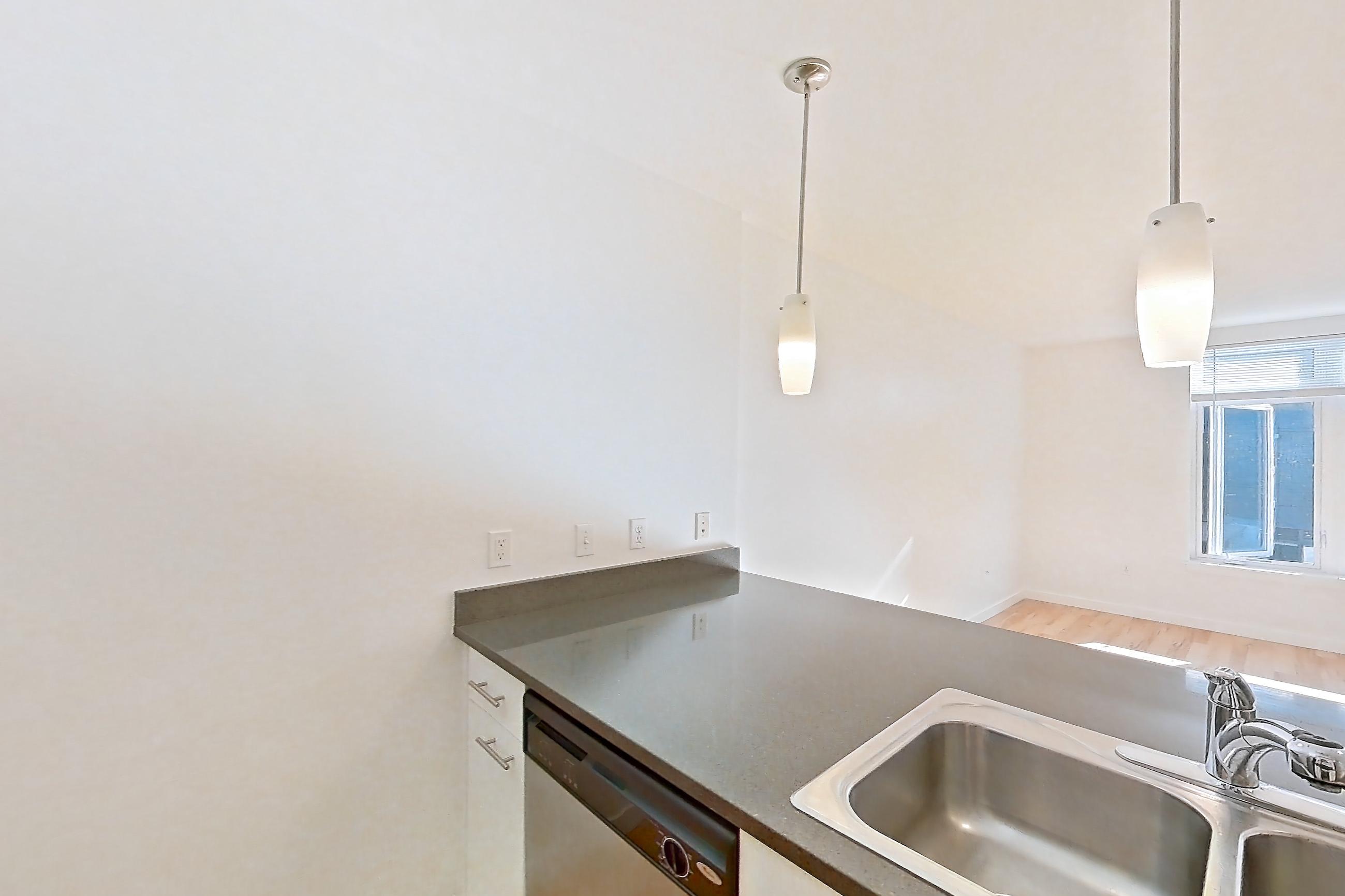 Kitchen with dark countertops, dishwasher, electric range, light countertops, light wood-finish flooring, microwave, oven/range, refrigerator, and stainless steel appliances, Apartment 0255 at Circa Greenlake