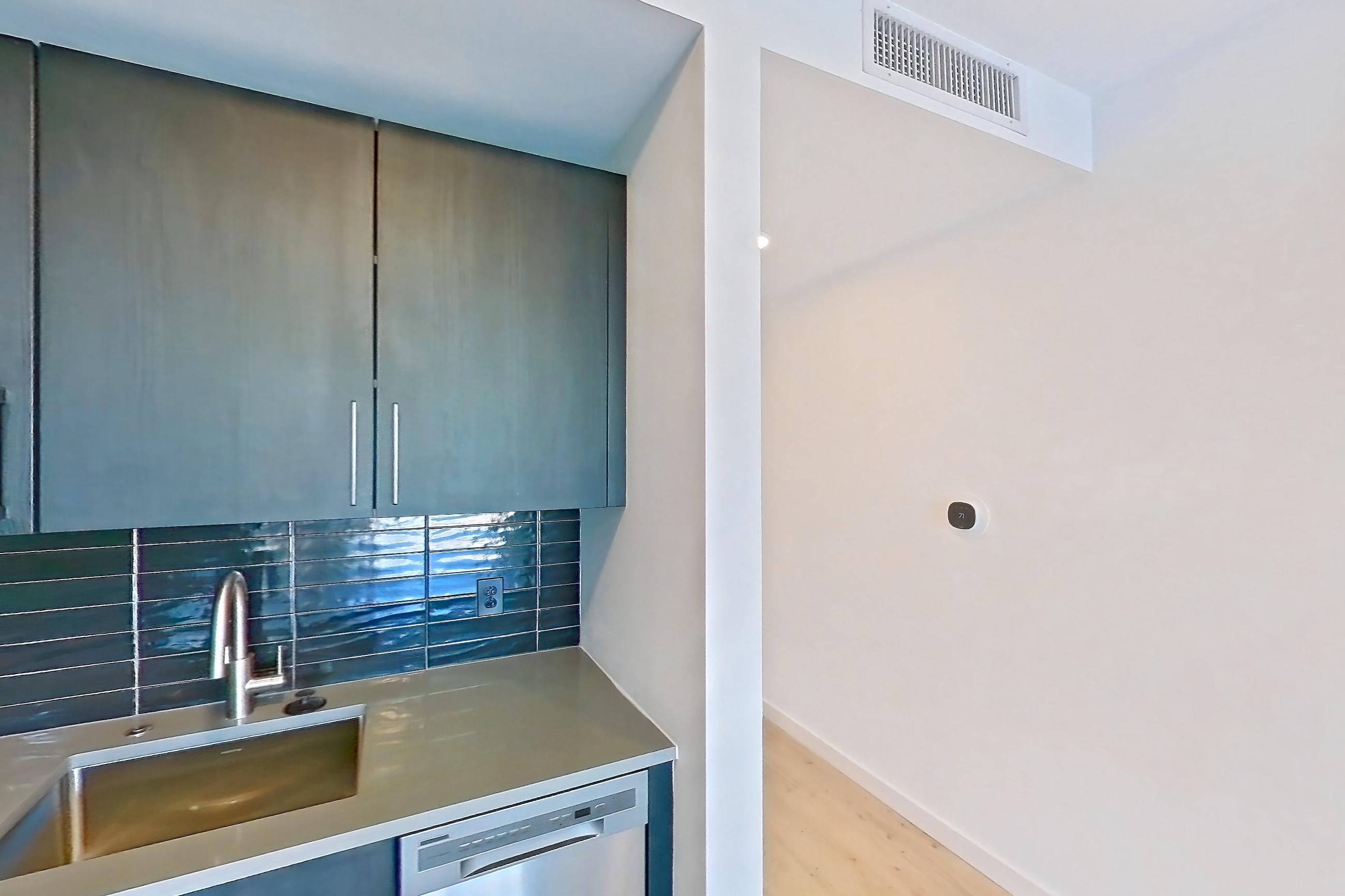 Kitchen with dishwasher, electric range, light countertops, light wood-finish flooring, oven/range, refrigerator, and stainless steel appliances, Apartment 404 at The Citizen