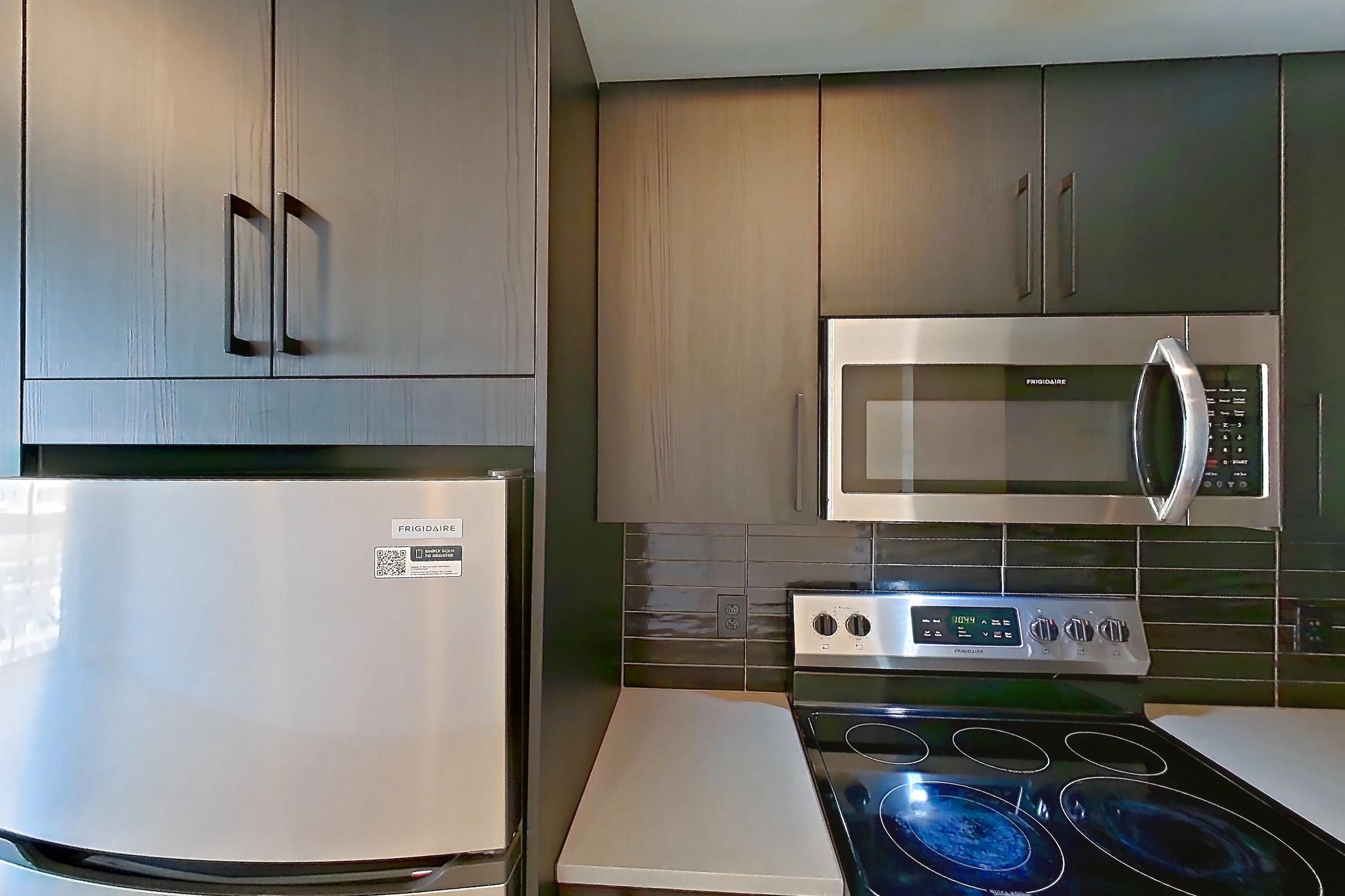 Kitchen with dishwasher, electric range, light countertops, light wood-finish flooring, oven/range, refrigerator, and stainless steel appliances, Apartment 404 at The Citizen
