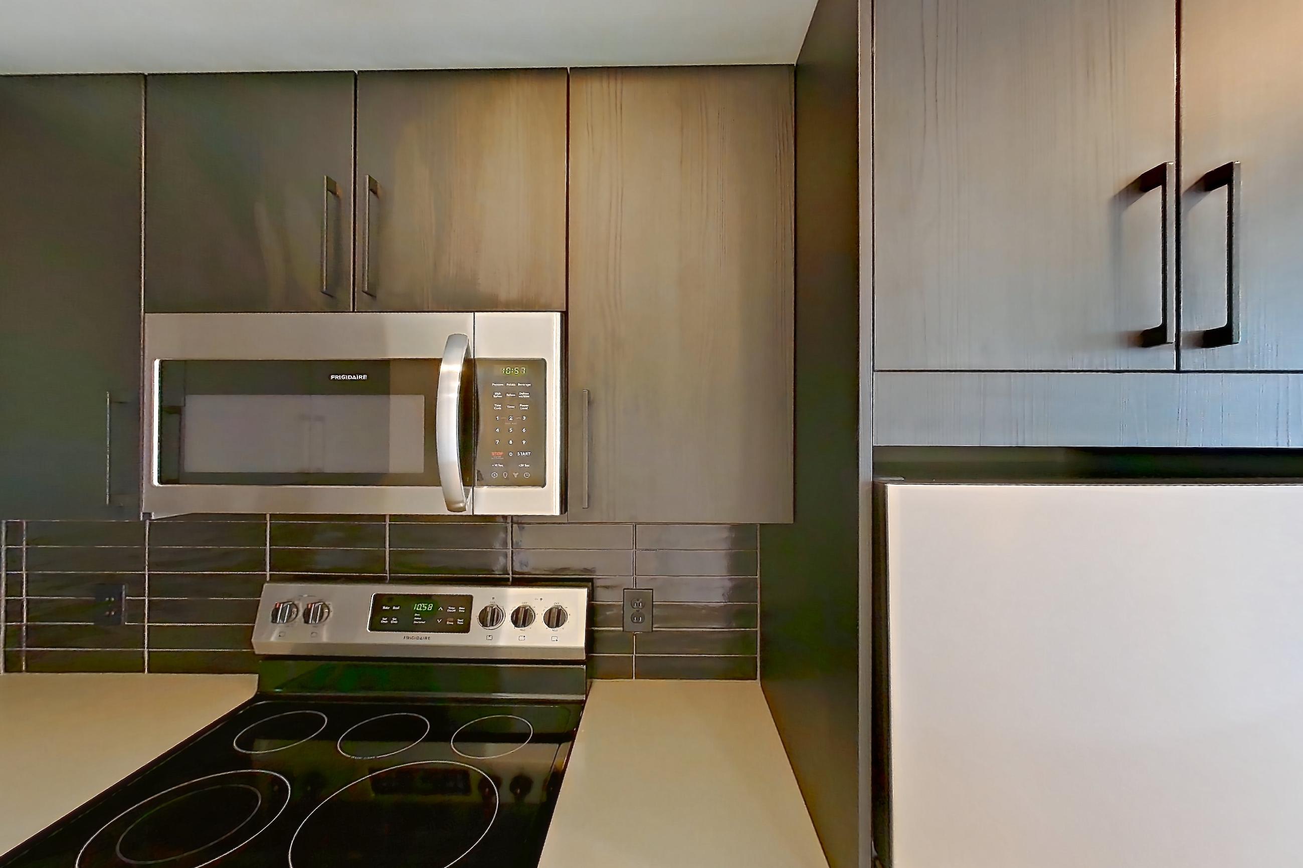 Kitchen with dishwasher, electric range, light countertops, light wood-finish flooring, microwave, oven/range, refrigerator, stainless steel appliances, and white appliances, Apartment 518 at The Citizen