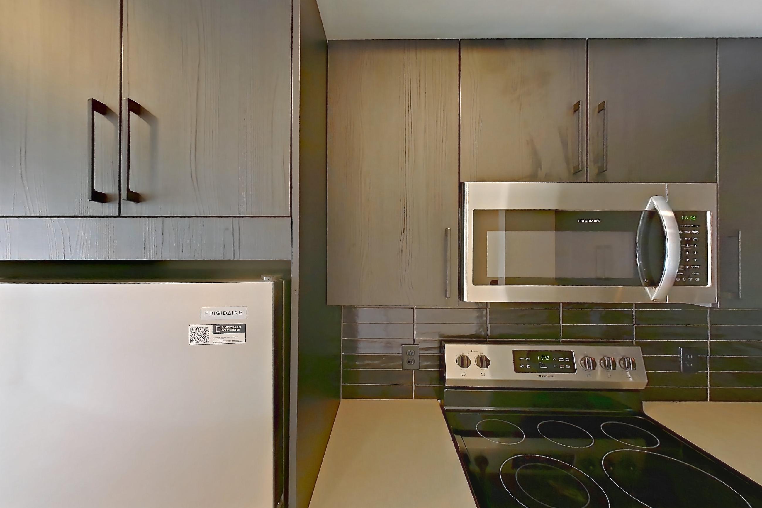 Kitchen with dishwasher, electric range, light countertops, light wood-finish flooring, microwave, oven/range, refrigerator, stainless steel appliances, and white appliances, Apartment 520 at The Citizen