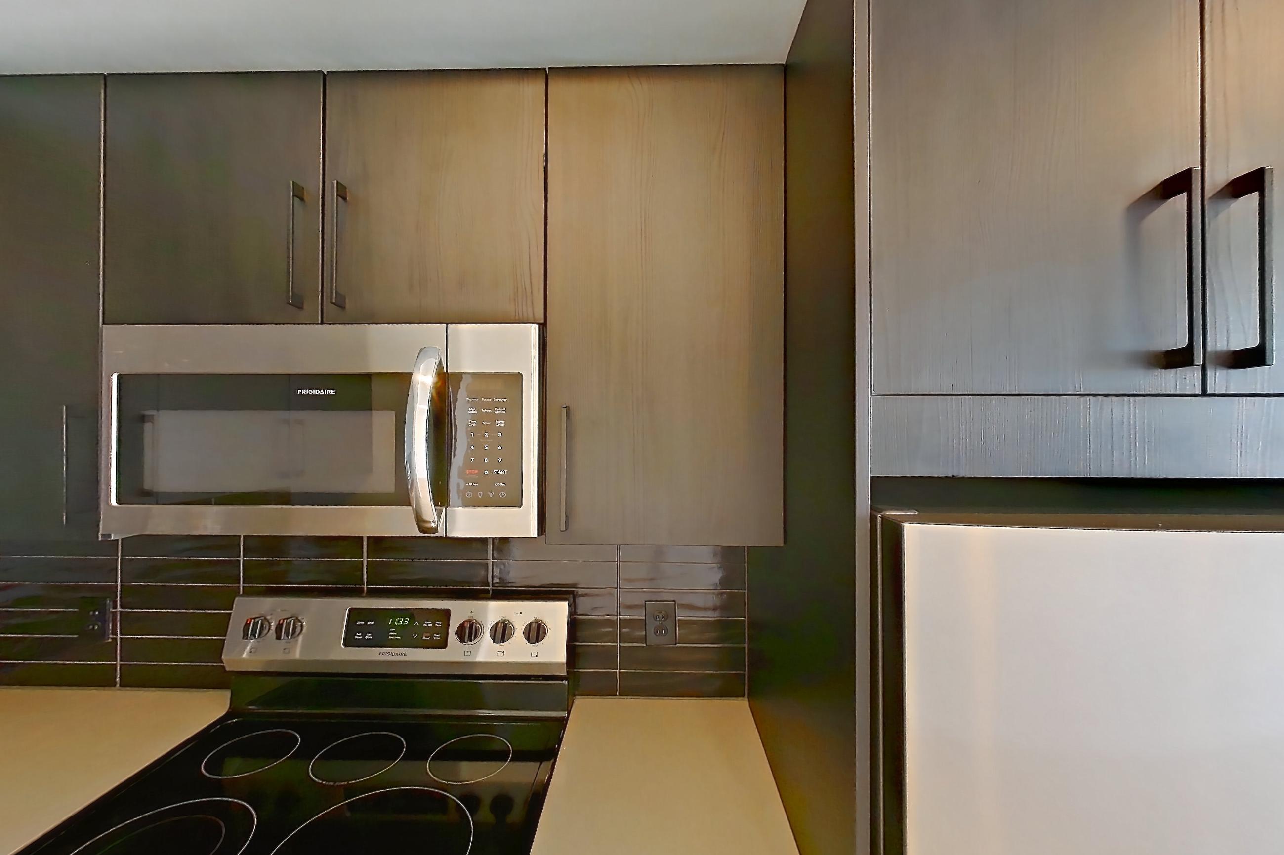 Kitchen with dishwasher, electric range, light countertops, light wood-finish flooring, microwave, oven/range, refrigerator, stainless steel appliances, and white appliances, Apartment 609 at The Citizen