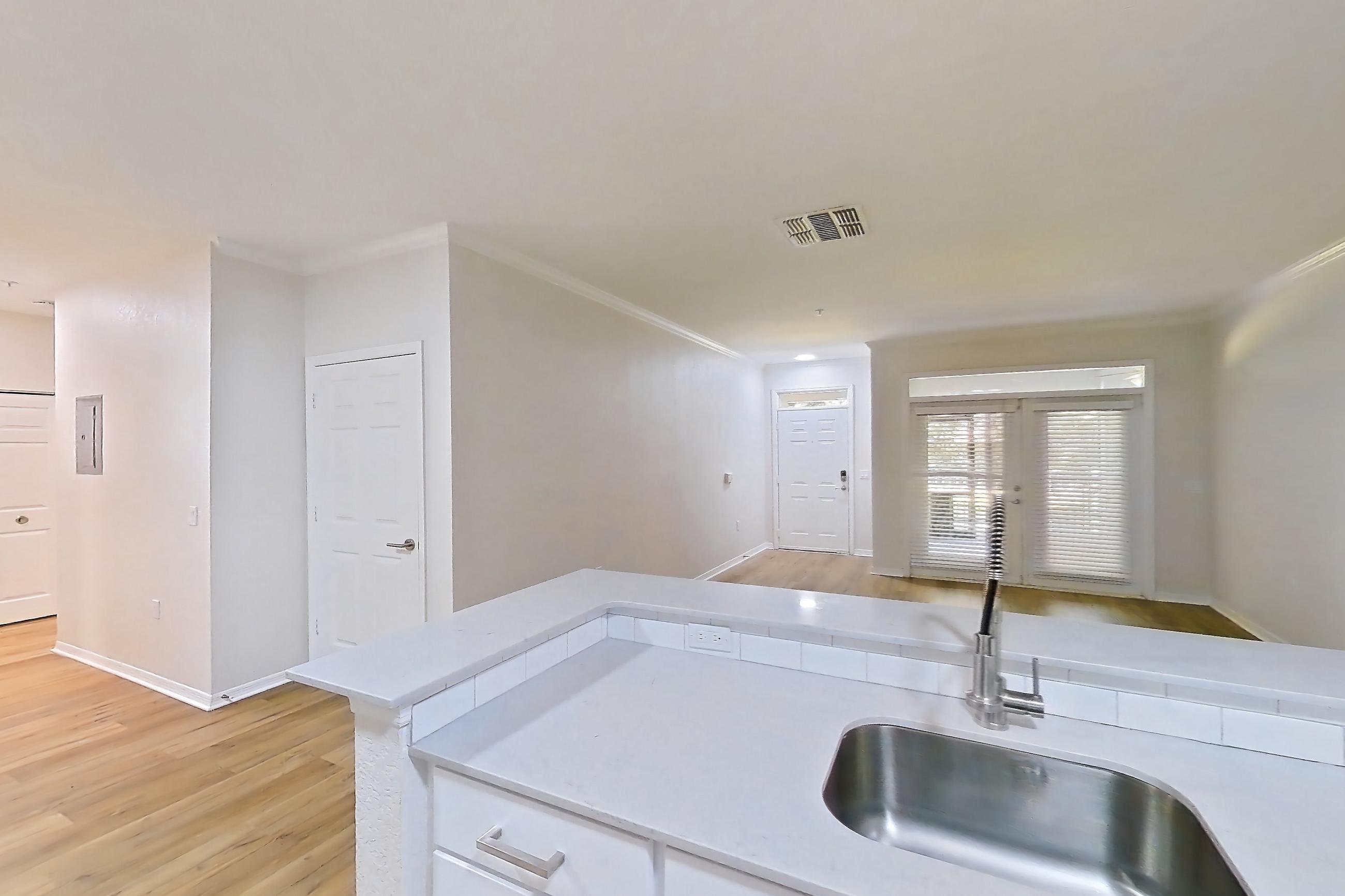 Kitchen with dishwasher, electric range, light countertops, light stone countertops, light wood-finish flooring, microwave, oven/range, refrigerator, and stainless steel appliances, Apartment 102 at Tortuga Bay