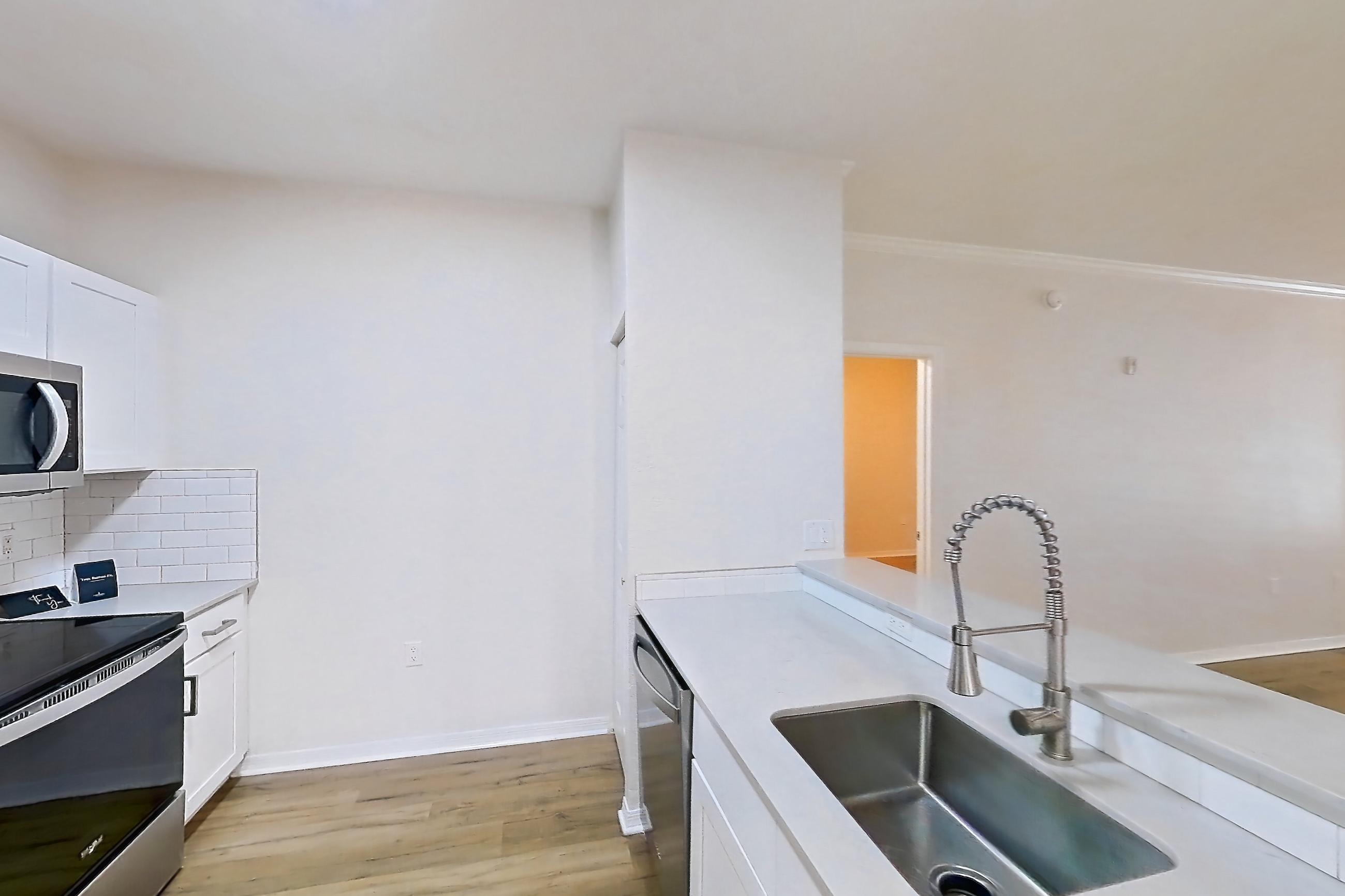 Kitchen with dishwasher, light stone countertops, light wood-finish flooring, refrigerator, and stainless steel appliances, Apartment 101 at Tortuga Bay